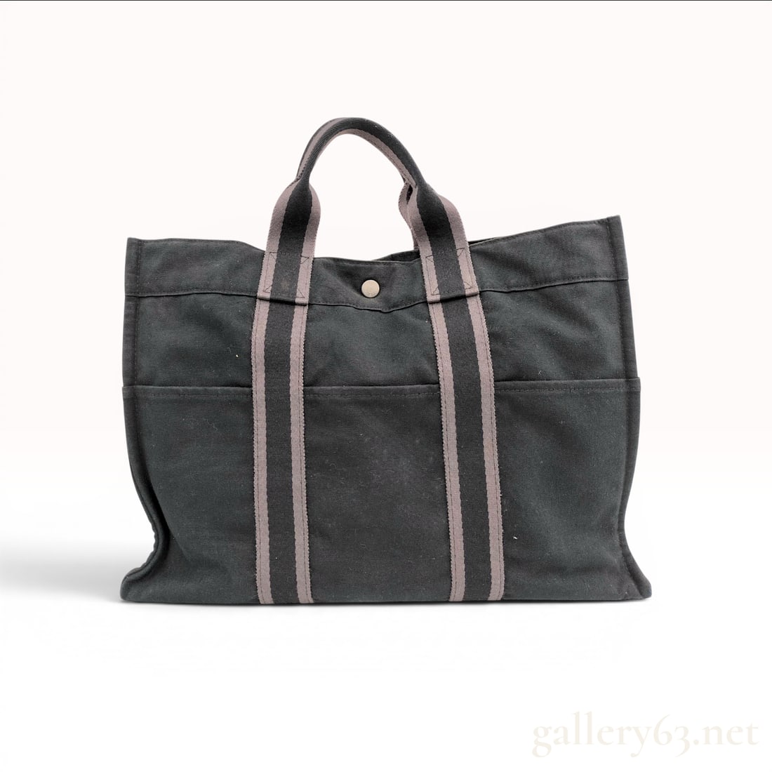 Hermes Fourre-tout GM Canvas Tote Bag: This Hermes Fourre-tout GM (Grand Modele) tote bag is crafted from heavyweight cotton canvas in a dark charcoal black hue. The bag features signature striped webbing top handles in gray and black that