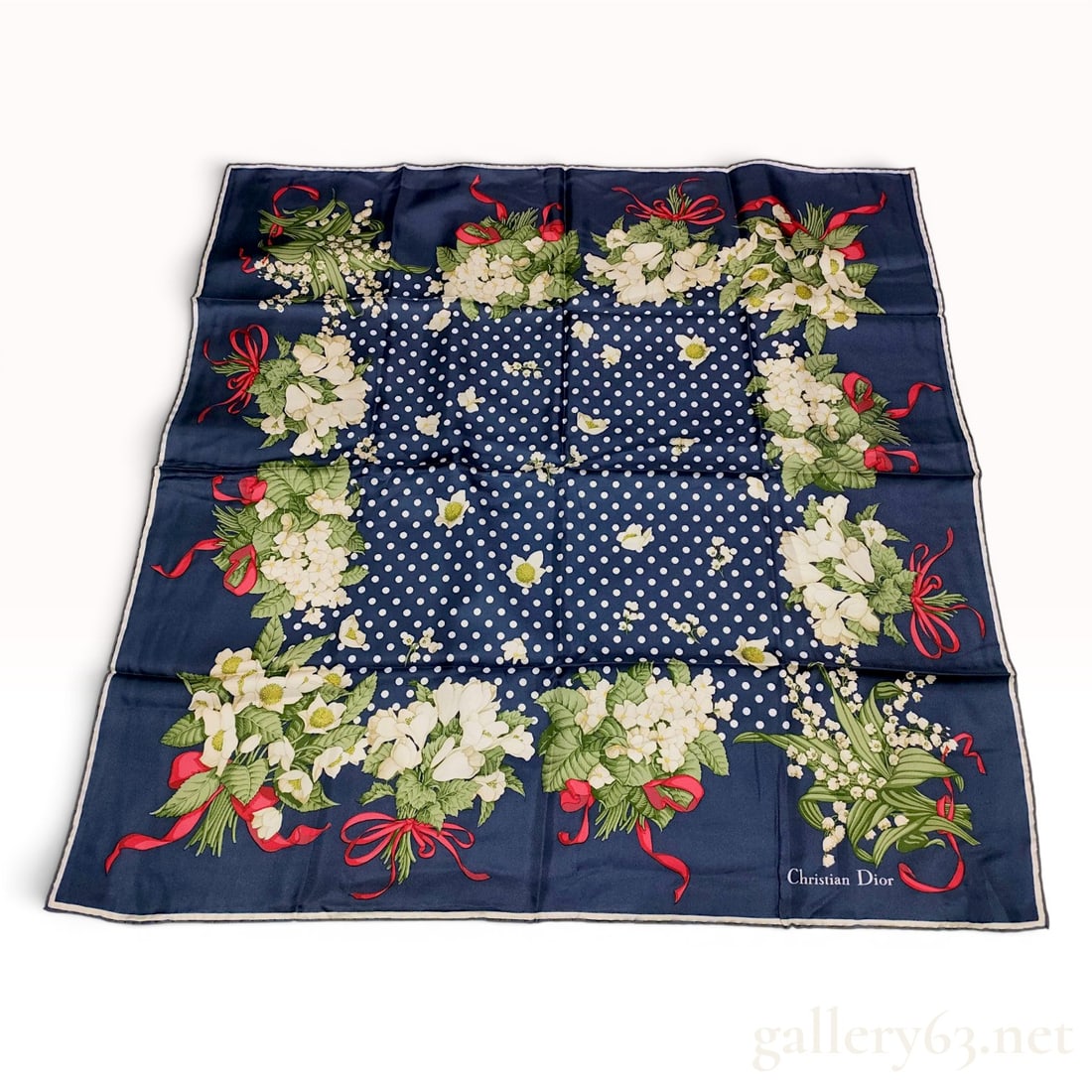 Christian Dior Vintage Silk Scarf with Lily of the Valley and Hellebore Motif: This vintage square silk scarf by Christian Dior features a dark navy blue ground with a central field of white polka dots. The border is decorated with a series of large floral bouquets consisting of