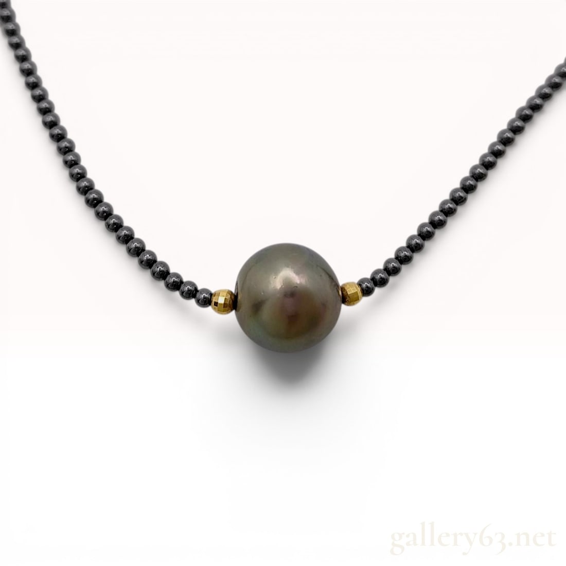 Tahitian Cultured Pearl and Black Spinel Necklace in 18K Yellow Gold: This contemporary necklace features a single round Tahitian cultured pearl as the focal point. The pearl displays a dark charcoal grey body color with iridescent peacock and green overtones and a high