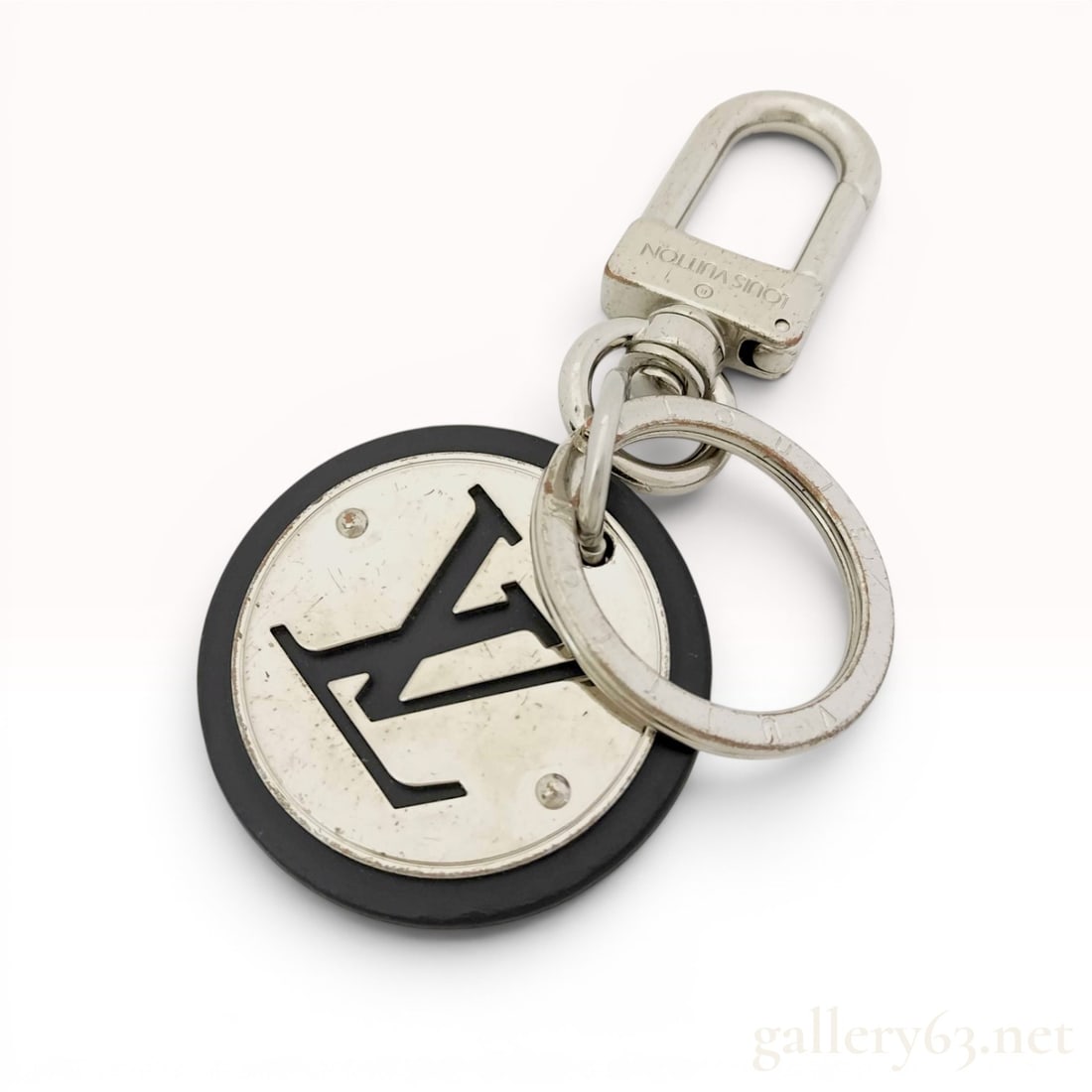 Louis Vuitton Neo LV Club Key Ring and Bag Charm: A Louis Vuitton Neo LV Club key ring and bag charm. The accessory features a circular charm with a silver-tone metal center and a cutout of the signature LV monogram logo, set within a black compositi