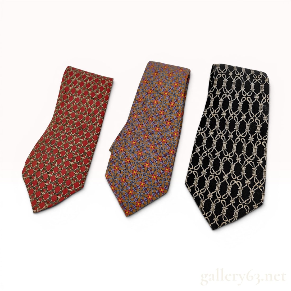 Three Hermes 100% Silk Printed Neckties: A set of three men's neckties by Hermes, Paris, constructed from 100 percent silk. The collection features three distinct geometric and figurative patterns. The first tie is red and features an intric