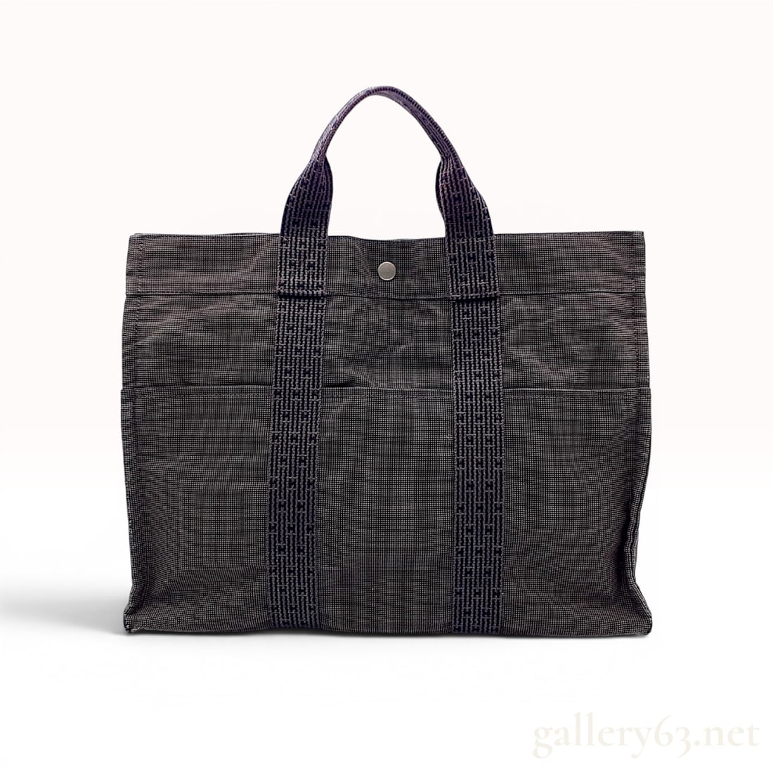 Hermes Herline Fourre Tout MM Canvas Tote Bag: A Hermes Herline Fourre Tout MM tote bag manufactured from a grey and graphite two-tone woven canvas. The exterior features signature vertical canvas straps incorporating a woven H motif throughout th