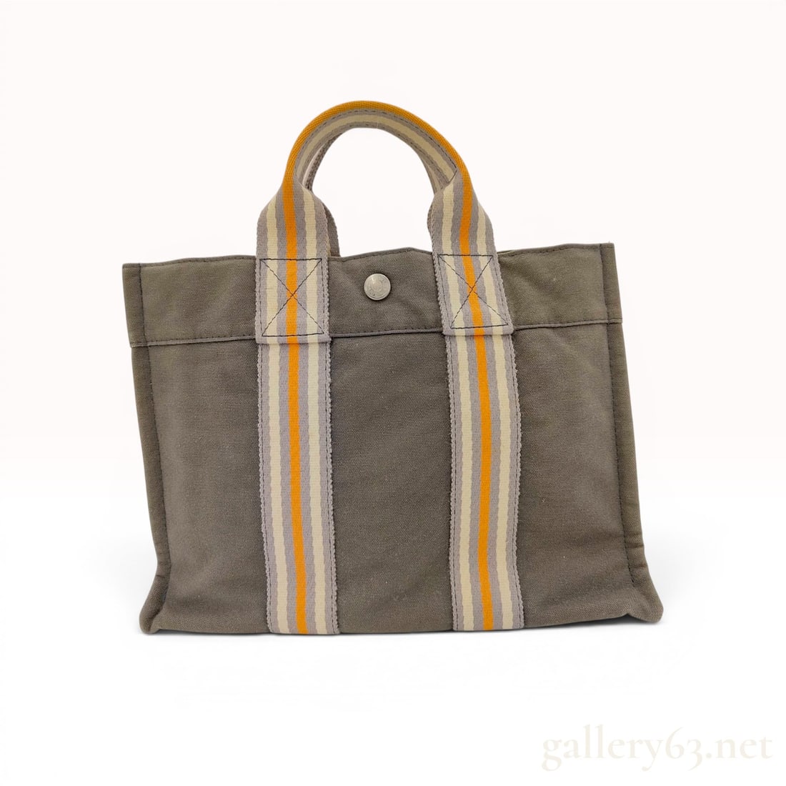 Hermes Troca Horizontal PM Canvas Tote Bag: This Hermes Troca Horizontal PM tote bag is constructed from heavy-duty dark grey canvas. The design features a distinct horizontal band across the upper portion and four exterior slip pockets integra