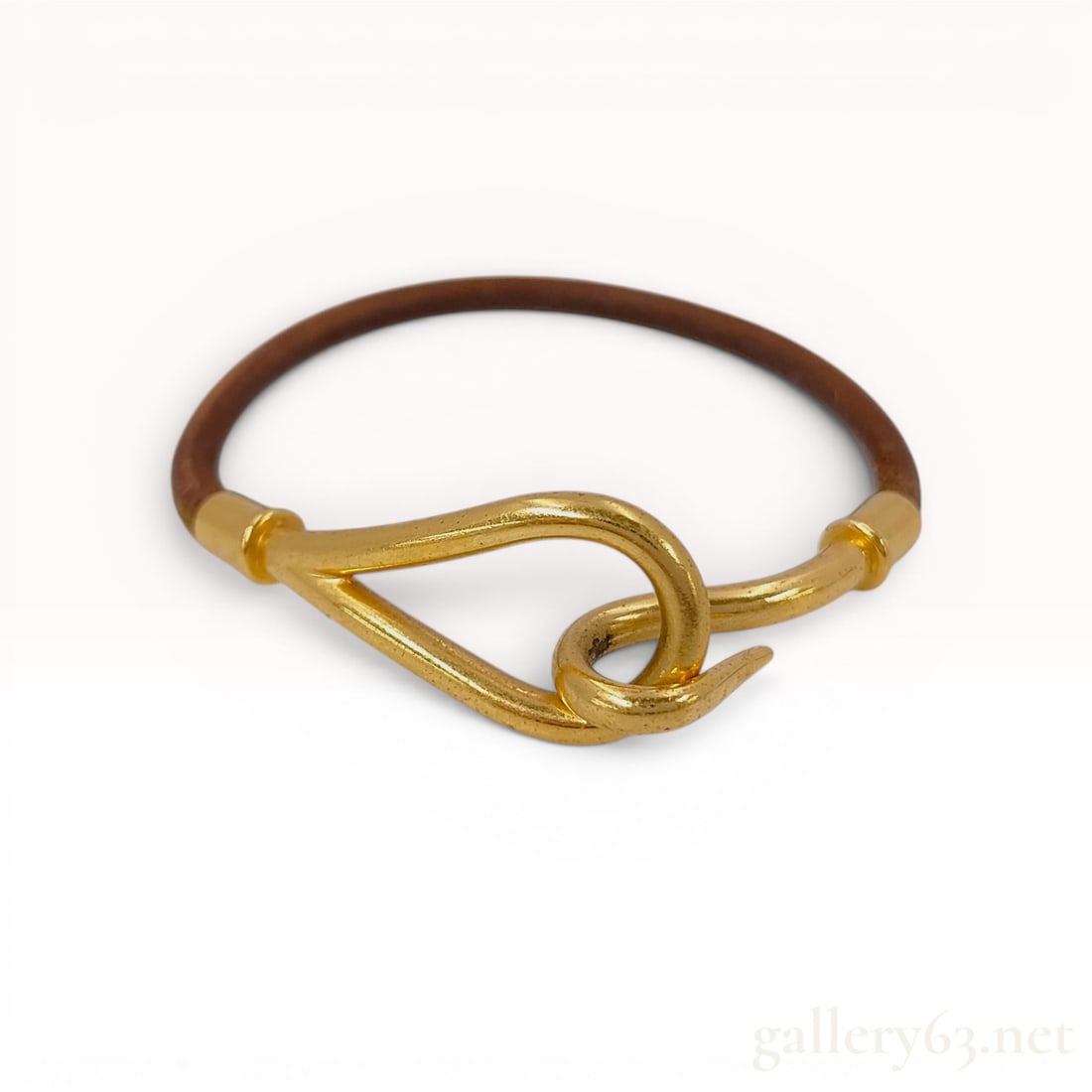 Hermes Brown Leather Jumbo Bracelet with Gold-PlatedHardware: Hermes Jumbo bracelet featuring a brown leather cord and gold plated hardware. The design utilizes a signature hook-and-eye clasp mechanism. The shank of the metal hook is incised with the maker mark 