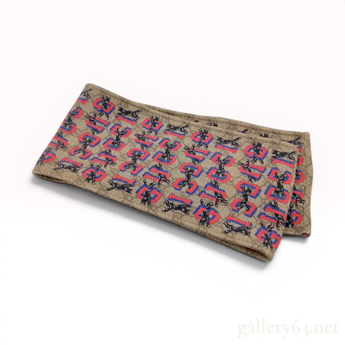 Gucci Silk Neck Bow with Wolf Motif and GG Supreme Pattern: A Gucci neck bow or ribbon scarf featuring a dual-sided design. The primary side is decorated with a printed pattern consisting of a beige and ebony GG Supreme monogram background, overlaid with a rep
