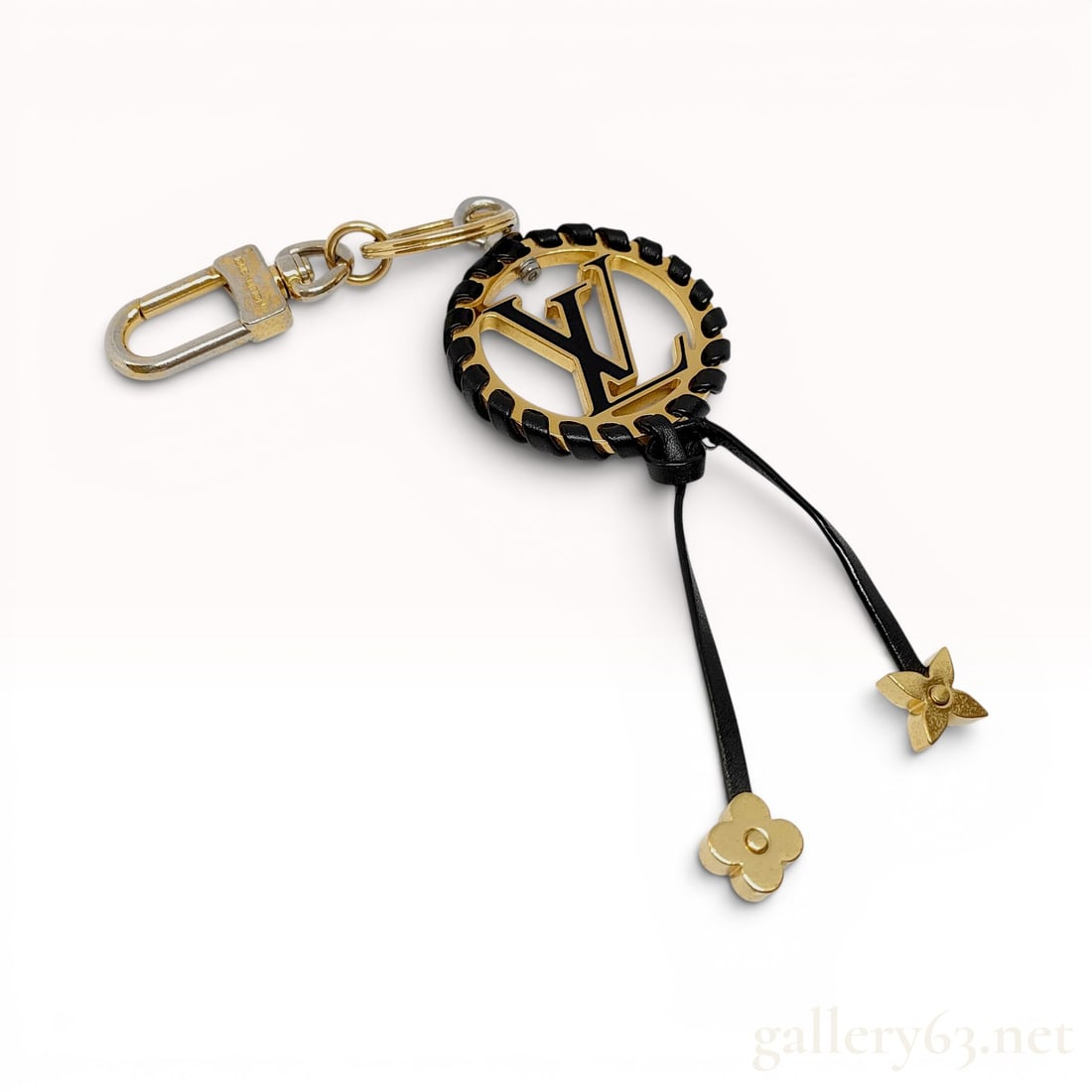 Louis Vuitton Very Bag Charm and Key Holder with Box: A Louis Vuitton "Very" bag charm and key holder. The accessory features a central gold-tone circular medallion with a black enamel-inlaid LV logo, finished with a hand-braided black leather 
