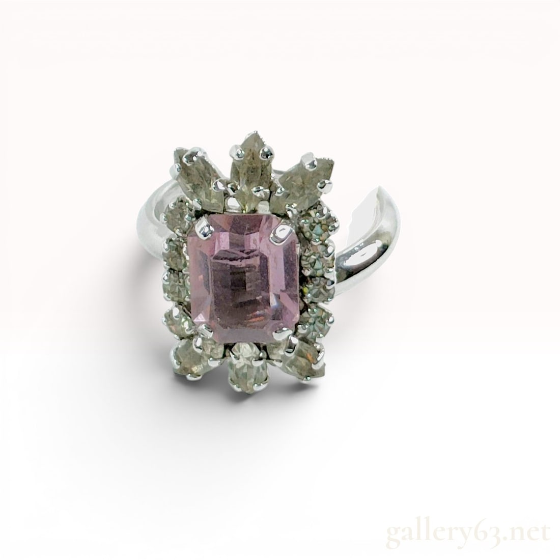 Christian Dior Vintage Cocktail Ring with Emerald Cut Pink Stone: A vintage costume cocktail ring by Christian Dior, manufactured in Germany. The piece features a central, rectangular emerald-cut pink glass stone held in a four-prong setting. This center stone is bo