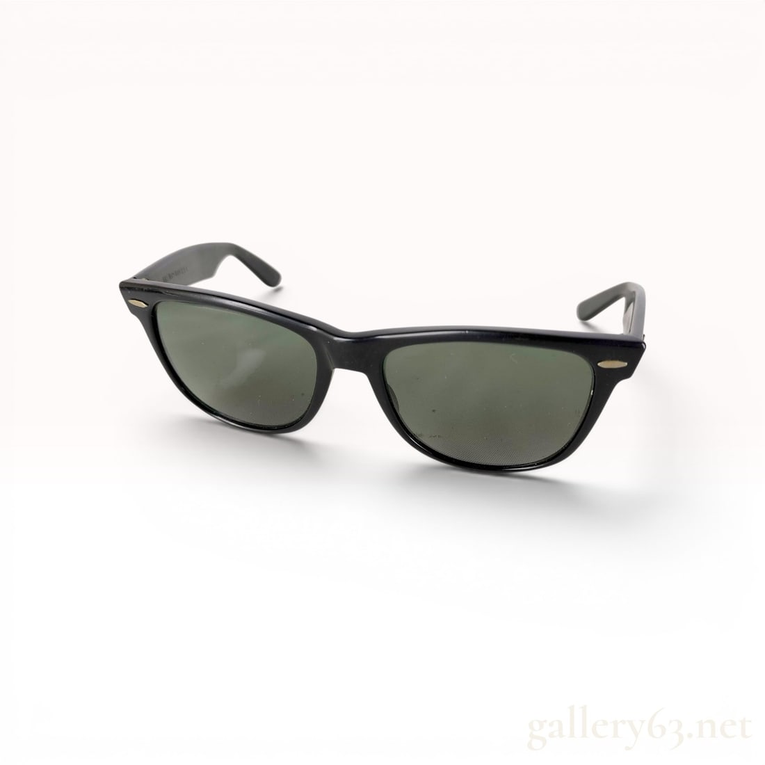 Bausch and Lomb Ray-Ban Wayfarer II Black Sunglasses: A pair of vintage Ray-Ban Wayfarer II sunglasses manufactured by Bausch and Lomb in the United States. The frames are composed of black acetate and house dark green glass lenses. The design features c