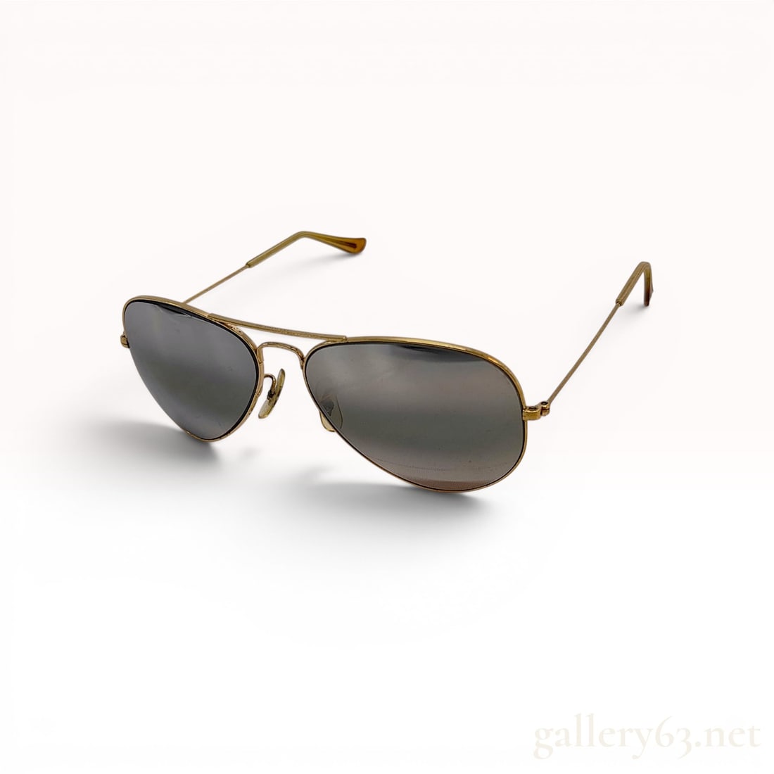 Vintage Bausch and Lomb Ray-Ban Gold Tone Aviator Sunglasses with Case: A pair of vintage Bausch and Lomb Ray-Ban aviator sunglasses. The eyewear features a classic gold-tone metal frame with a signature double bridge design. The dark-tinted glass lenses are housed in thi