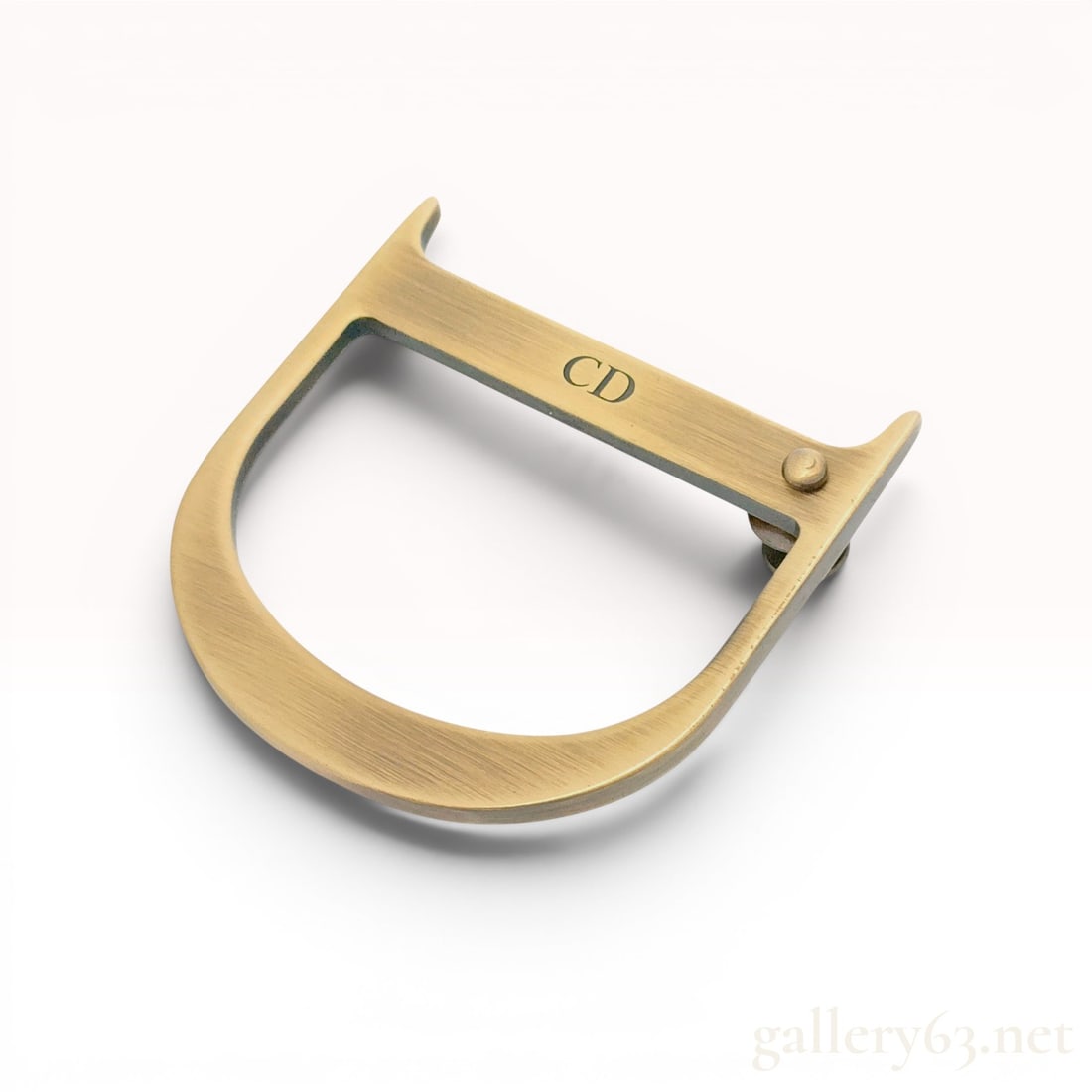 Christian Dior Antique Gold-Tone D-Shape Brooch Pin: Christian Dior decorative accessory designed in the distinctive D-shape representative of the brand's Saddle bag hardware. The piece is made of metal with a brushed antique gold-tone finish. The horiz
