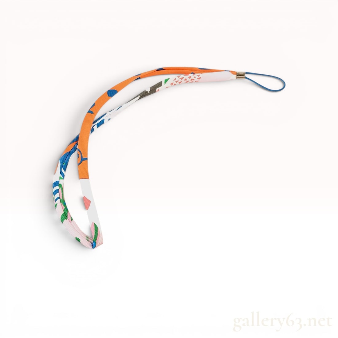 Hermes Printed Ribbon Twilly Strap: This accessory is a printed ribbon strap, commonly referred to as a Twilly strap, designed for use as a cell phone charm, camera lanyard, or decorative bag attachment. The strap is constructed from a 