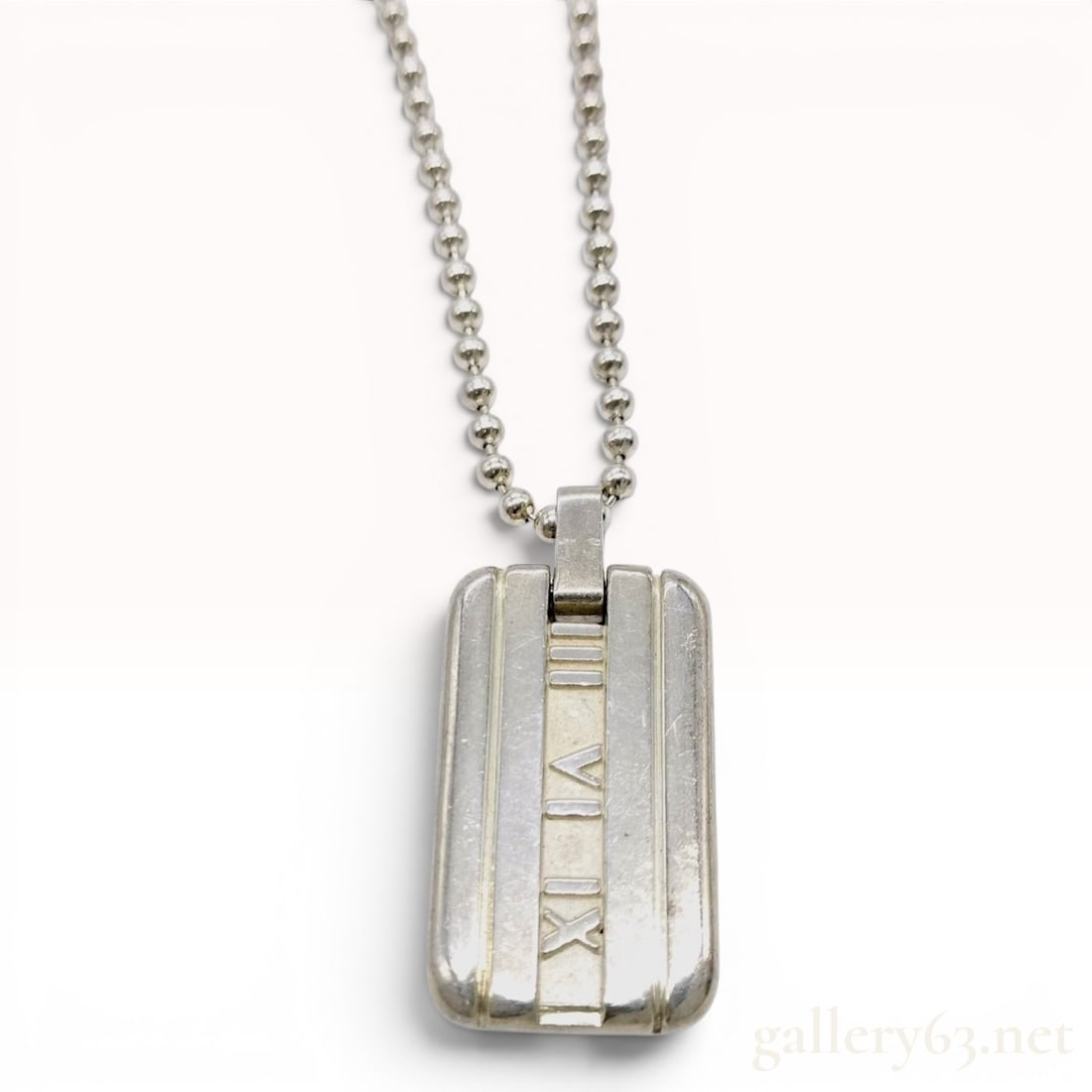 Tiffany & Co. Sterling Silver Atlas Dog Tag Pendant Necklace: A Tiffany & Co. sterling silver pendant necklace from the Atlas collection. The design features a rectangular dog tag style pendant with three horizontal recessed bands; the central band is detailed w