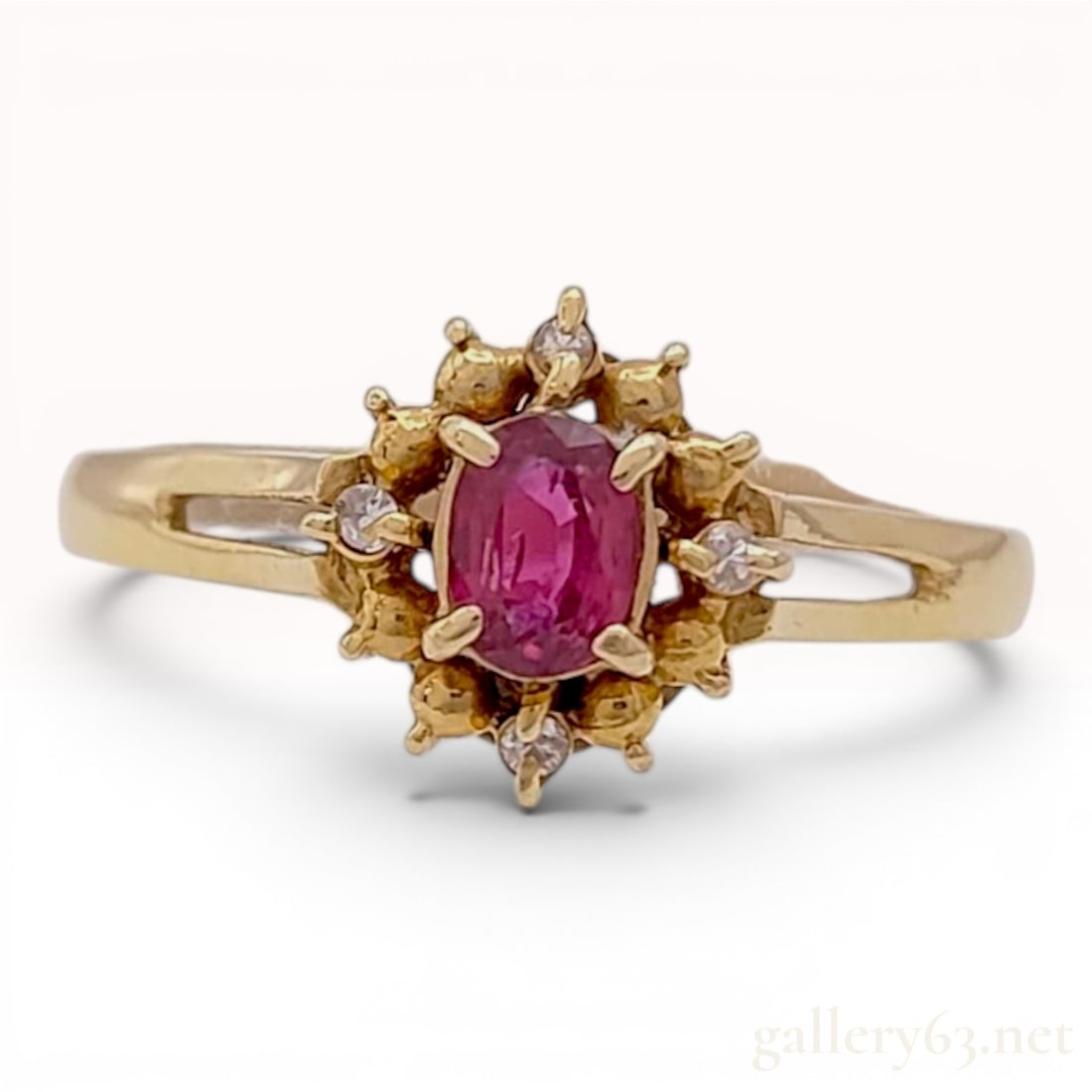 18 Karat Yellow Gold Ruby and Diamond Cluster Ring: This ring is constructed from 18 karat yellow gold and features a tiered cluster or cocktail style setting. The central focal point is an oval-cut purplish-red ruby, secured by four gold prongs.