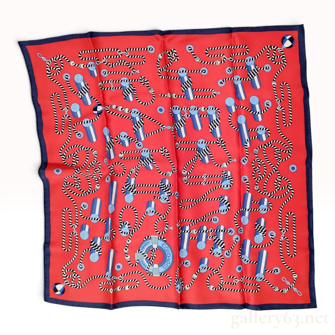 Hermes Cordages Silk 70cm Carre: An authentic Hermes silk 70cm carre, featuring the nautical Cordages pattern. The design illustrates stylized marine ropes, pulleys, and lifebuoys on a vibrant red field with a navy blue border. The g