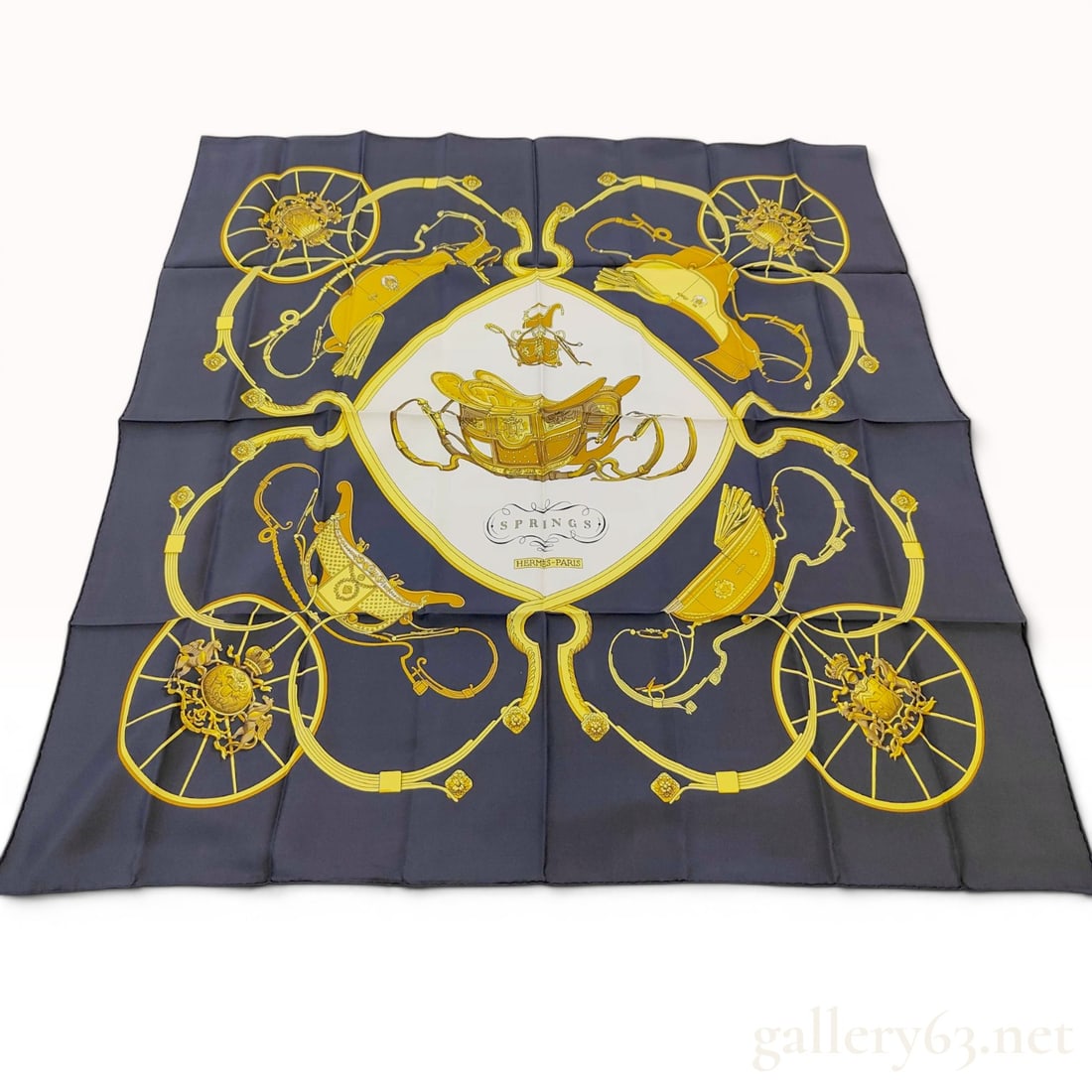 Hermes Springs Silk Carre 90 Scarf by Philippe Ledoux: This silk scarf from Hermes features the Springs pattern designed by Philippe Ledoux. The design depicts a central horse-drawn carriage set within a white diamond-shaped field. The surrounding navy bl