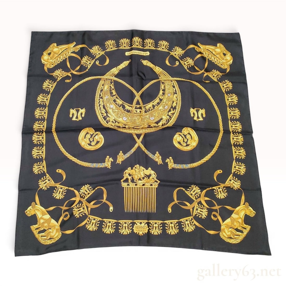 Hermes Les Cavaliers d'Or Silk Scarf: A vintage Hermes 90cm silk twill scarf in the Les Cavaliers d'Or pattern, designed by Vladimir Rybaltchenko. The design features a collection of Scythian gold jewelry artifacts, including the Great Pe