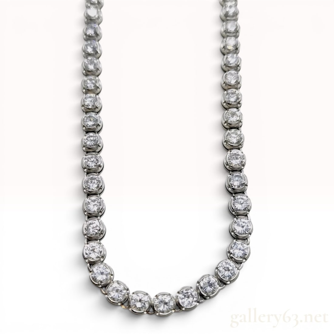 A Platinum and 10.00ctw Natural Diamond Graduated Tennis Necklace: This graduated diamond tennis necklace is composed of a continuous row of round brilliant-cut diamonds totaling 10.00 carats. The stones are individually secured in circular platinum bezel mountings t