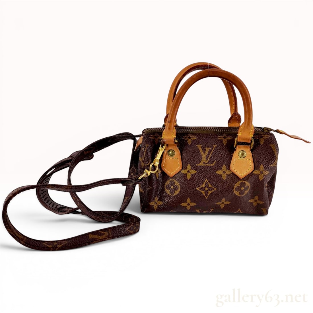 Louis Vuitton Monogram Canvas Mini Speedy HL Handbag with Strap: A Louis Vuitton Mini Speedy HL handbag crafted from signature monogram coated canvas with natural vachetta leather trim and dual rolled top handles. This miniature version of the classic Speedy bag in