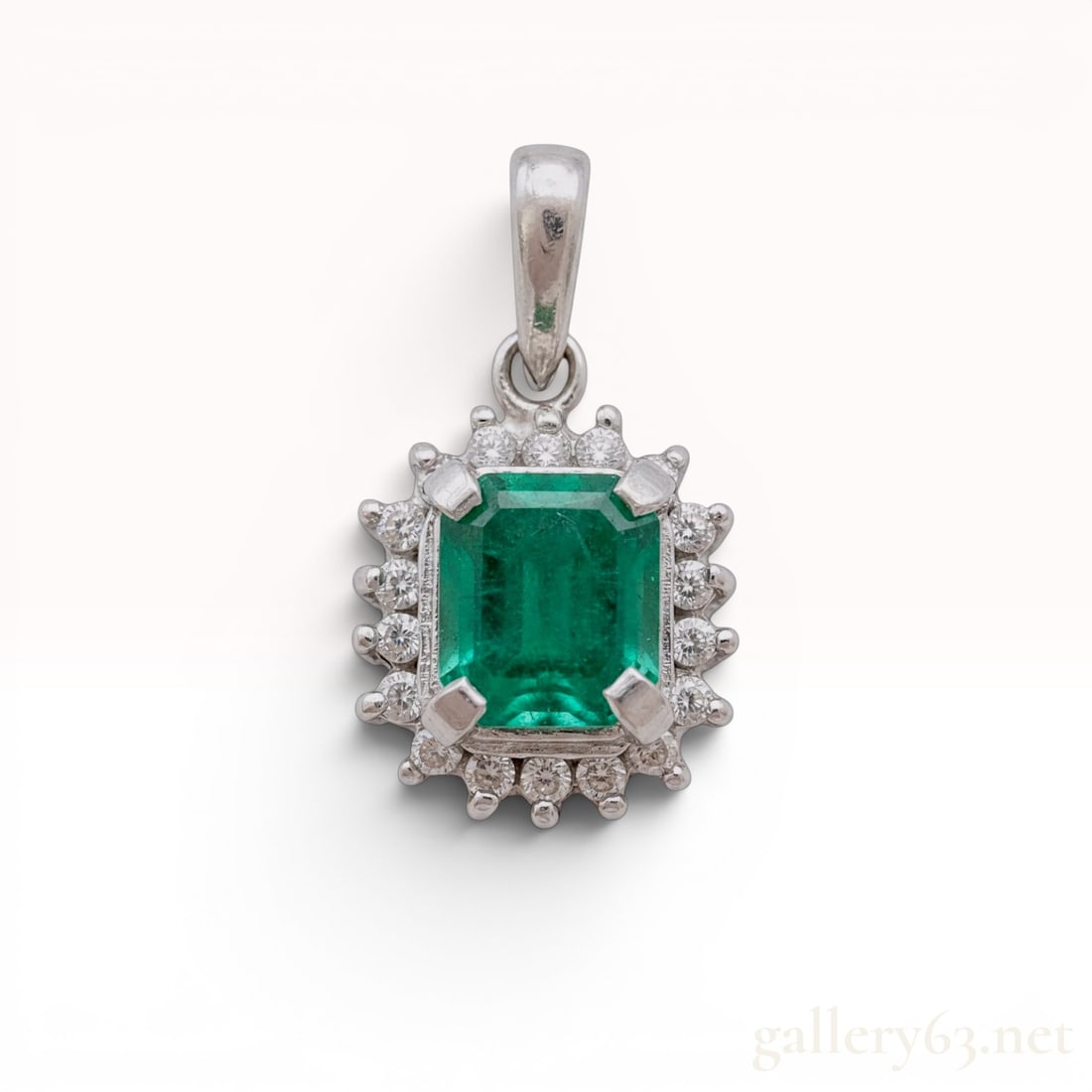 Platinum 0.93ct Emerald-Cut Emerald and Diamond Halo Pendant: This platinum pendant features a central emerald-cut natural emerald secured in a four-prong mounting. The center stone is framed by a halo of small round-cut accent diamonds. The bail is stamped with