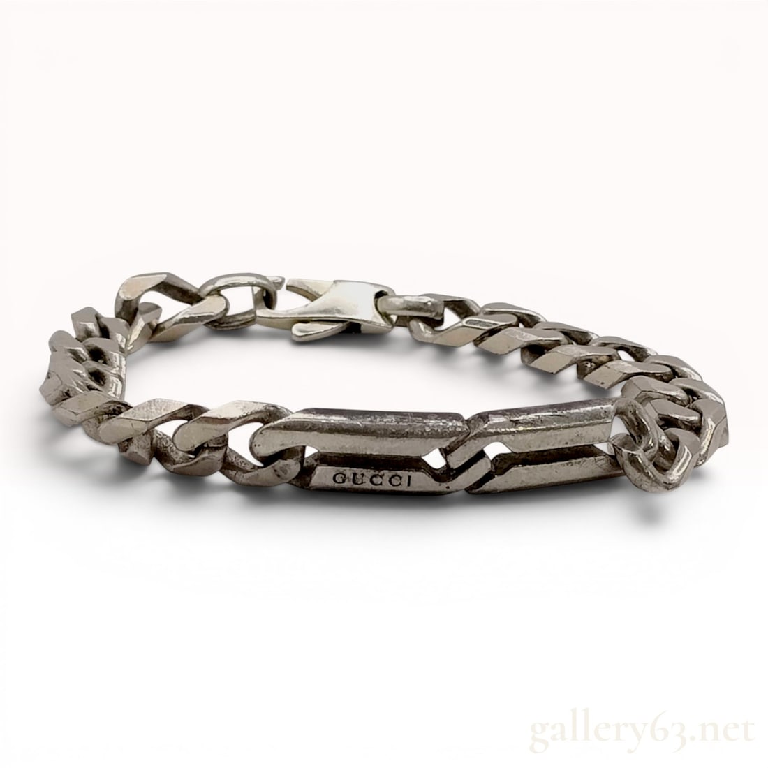 Gucci Sterling Silver Interlocking Curb Link Bracelet: A sterling silver curb link bracelet by Gucci featuring a central interlocking bar element. The design consists of heavy, angular gourmette links joined to a two-part central bar with an interlocking 