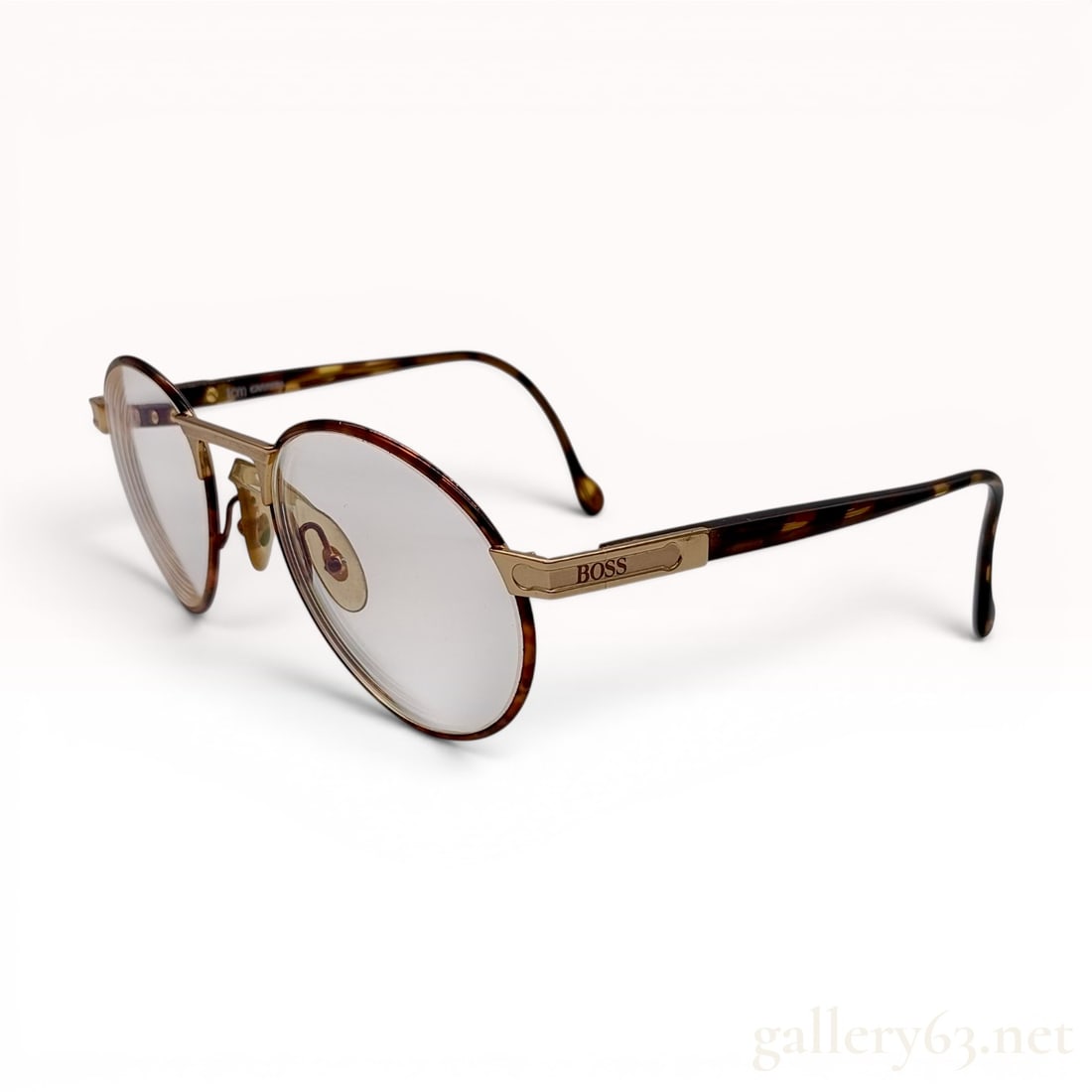 Hugo Boss by Carrera Model 5154 Vintage Oval Eyeglasses: This pair of vintage Hugo Boss by Carrera eyeglasses, model 5154, features an oval frame design. The frames are constructed from tortoiseshell-patterned acetate rims joined by a textured, gold-tone me