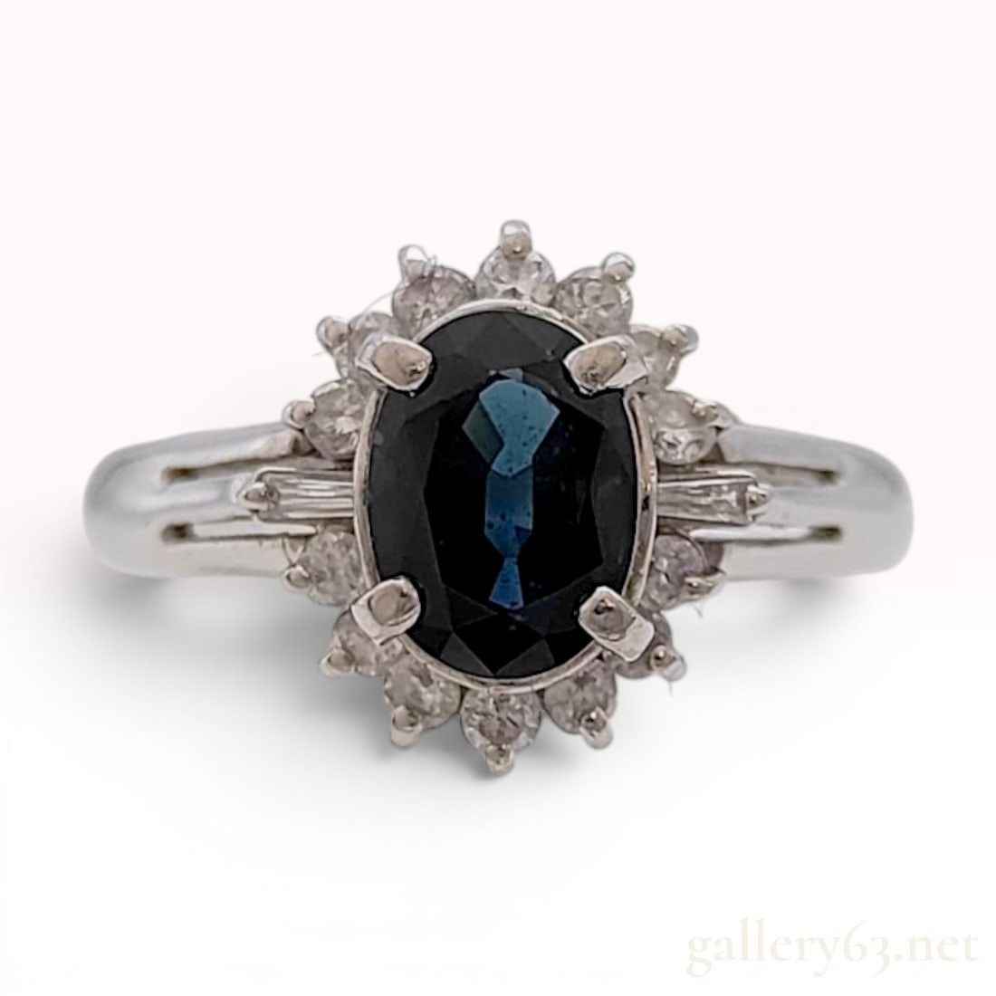 Camellia Sapphire and Diamond Halo Ring in Platinum: This cocktail ring is crafted in platinum and features a central oval-cut sapphire of a deep blue hue. The primary stone is secured in a four-prong setting and surrounded by a halo of round diamonds. 