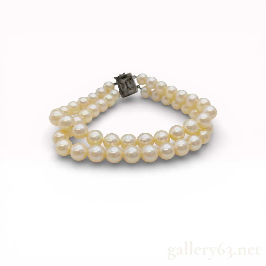 Vintage Cultured Pearl Two Strand Bracelet with Sterling Silver Clasp: A vintage double-strand bracelet featuring two rows of uniform, cream-toned cultured pearls. The pearls exhibit a lustrous finish. The piece is secured with a rectangular silver box-style clasp design