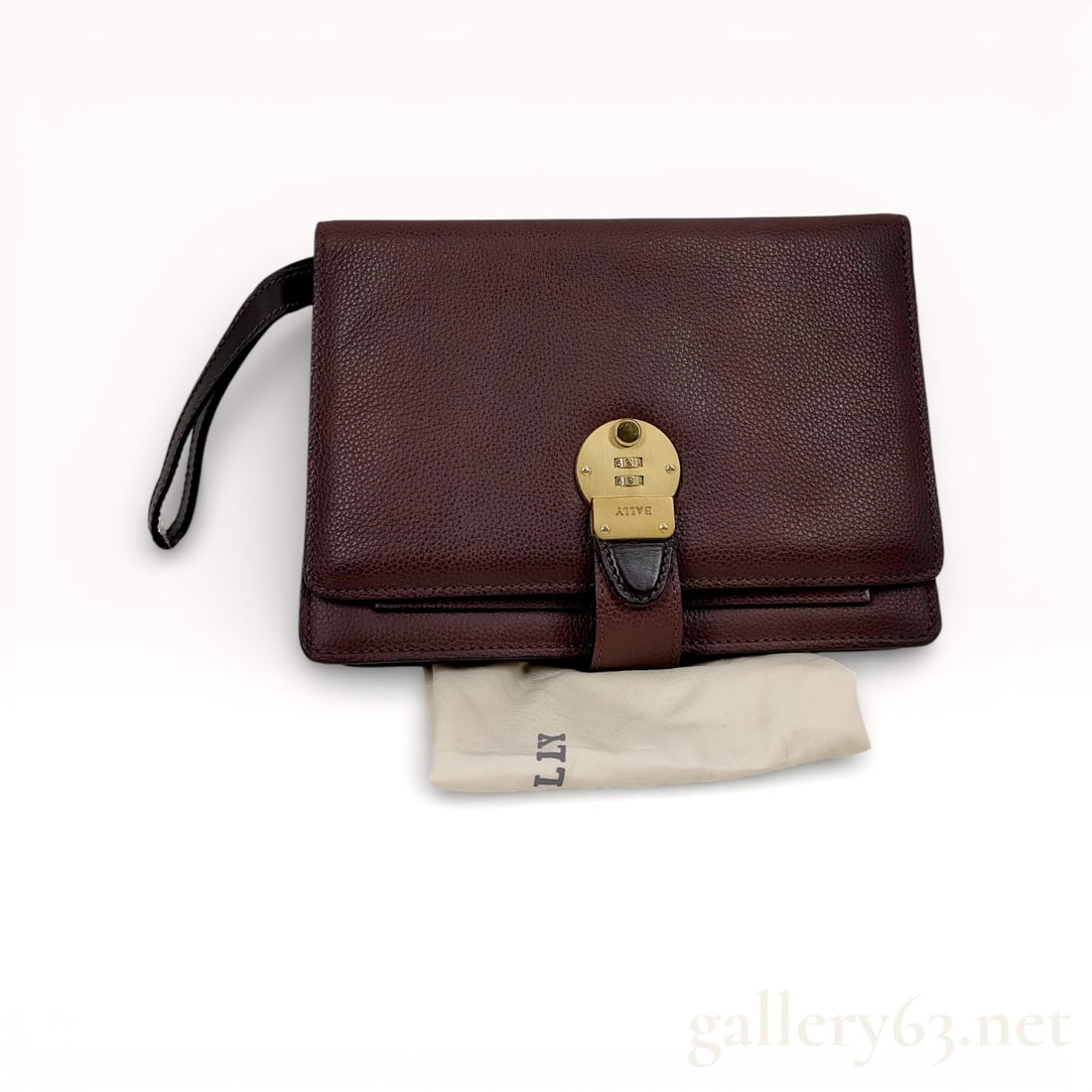 Bally Dial Leather Clutch with Wrist Strap: Bally leather clutch having a structured rectangular form in dark brown grained leather. Front flap secured with a strap and round gold-tone Dial hardware element stamped with branding details. Slim w