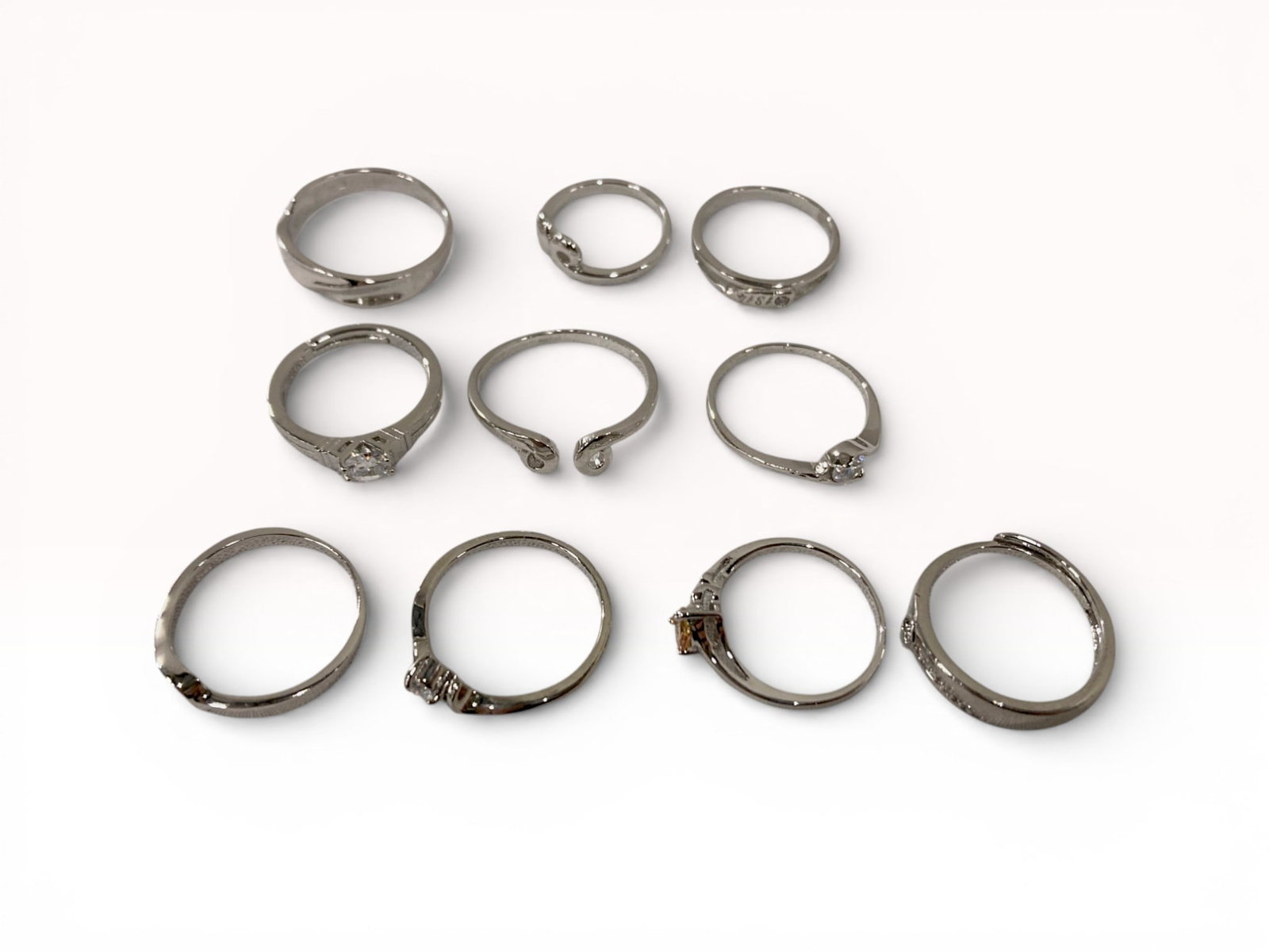 Silver and Silver-Tone Mixed Fashion Rings with Synthetic Cubic Zirconia: This lot features a collection of ten contemporary fashion rings in various silver-tone finishes. The assortment includes two engagement-style solitaire rings featuring round brilliant-cut synthetic s