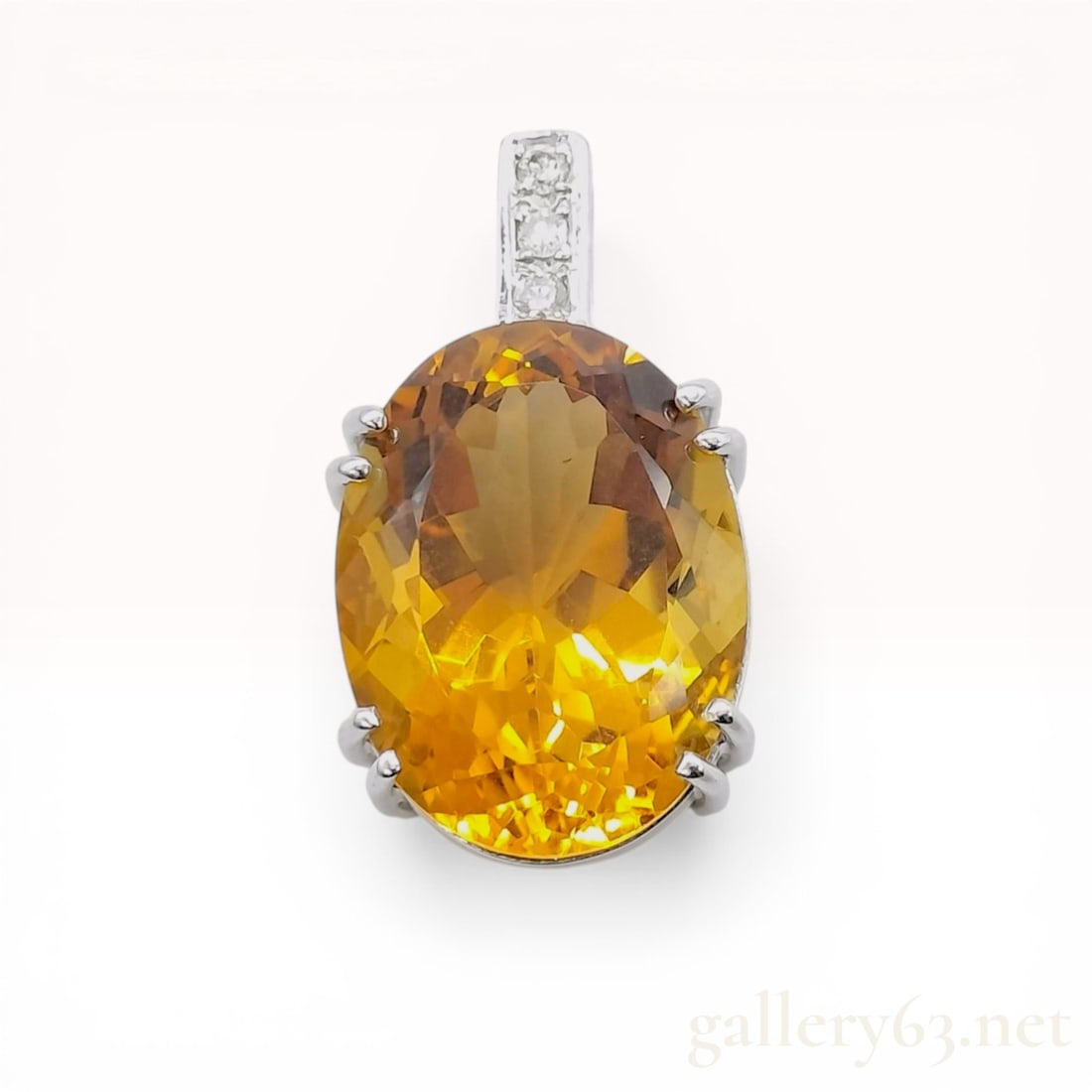 18 Karat White Gold Citrine and Diamond Pendant: An 18 karat white gold pendant featuring a large oval-cut citrine accented with diamonds. The primary honey-gold citrine is secured in an eight-prong basket setting with an open back. Three round bril