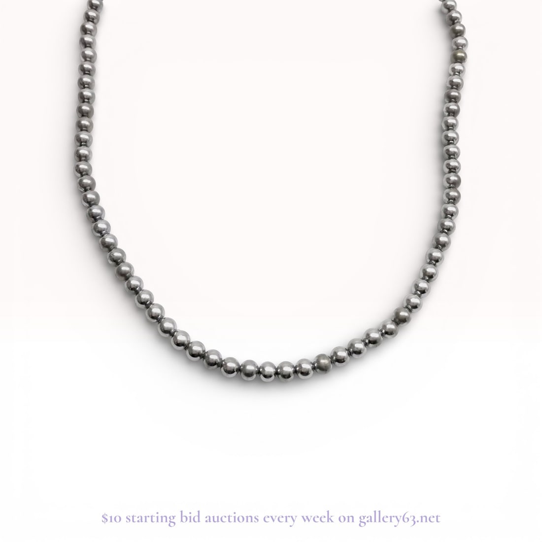 Single Strand Metallic Finish Bead Necklace with Filigree Clasp: Single strand bead necklace featuring uniform spherical beads with a reflective gunmetal gray metallic finish. The strand is hand-knotted and secured with a silver-tone oval filigree box clasp decorat