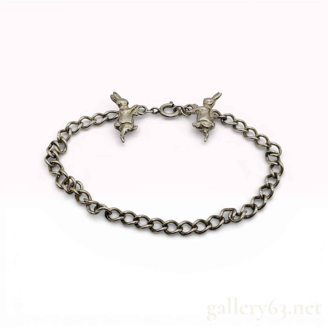 Sterling Silver Curb Link Bracelet with Figural Rabbit Charms: Sterling silver curb link bracelet featuring two integrated figural rabbit charms by the maker Kite. The charms are depicted in active poses and flank a spring ring clasp. One charm is incised with th