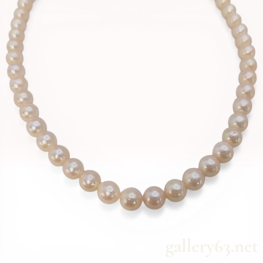 Cultured Freshwater Pearl Necklace with Silver Floral Clasp: A single strand of uniform round cultured freshwater pearls featuring a creamy white body color with rose overtones and high luster. The pearls measure approximately 7mm to 8mm in diameter and are pro