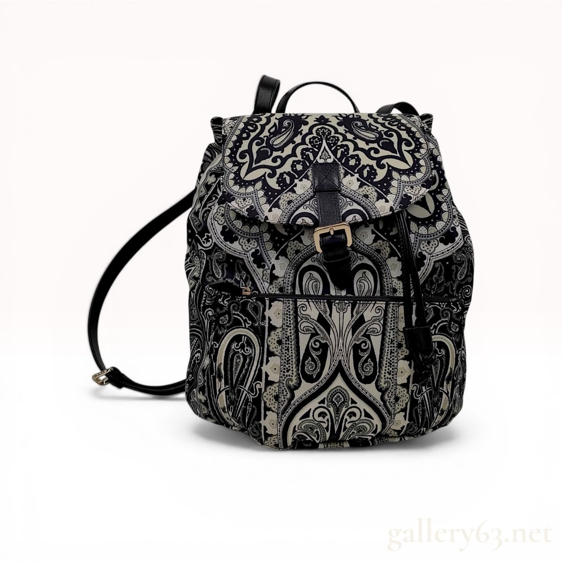 Etro Milano Monochrome Paisley Print Textile and Leather Backpack: Etro Milano drawstring backpack with a top flap and gold-tone magnetic snap closure. Constructed from a monochrome paisley print textile with black leather trim, top handle, and adjustable shoulder st