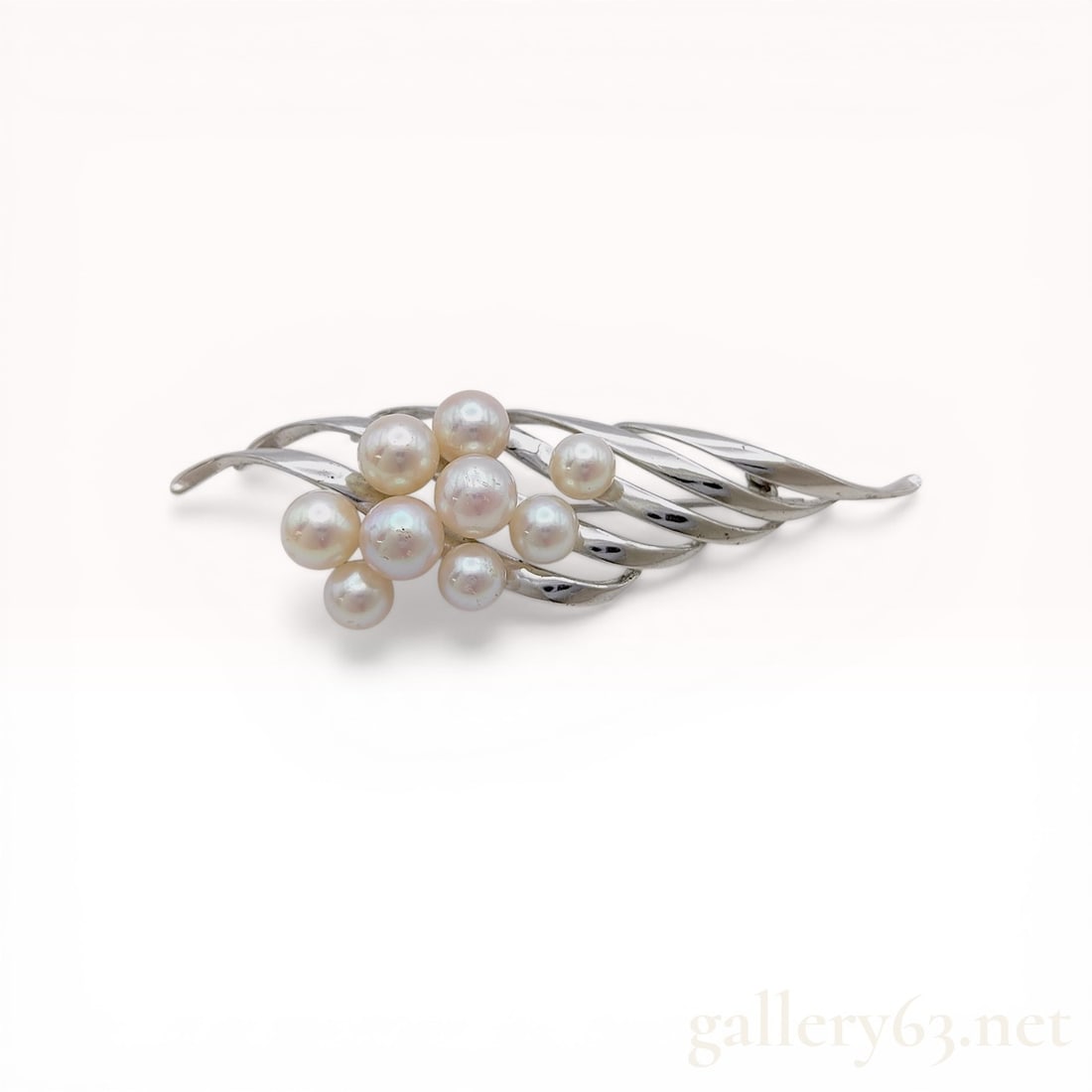 Mikimoto Sterling Silver and Cultured Pearl Spray Brooch: Mikimoto foliate spray brooch featuring ten graduated cultured pearls set in sterling silver, mid-20th century. The abstract design consists of curving silver bands cradling a cluster of pearls with c