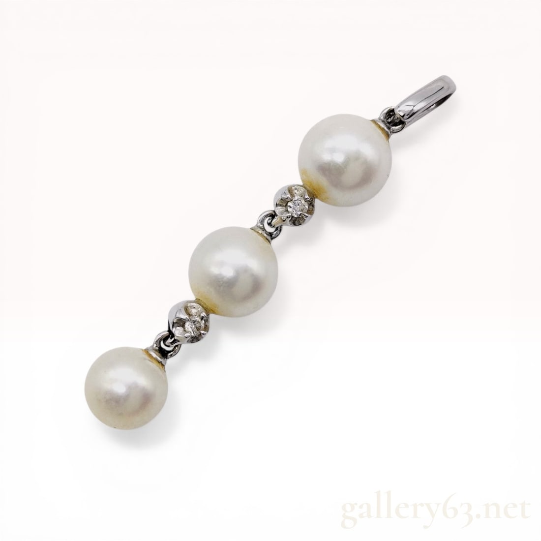 18K White Gold Pearl and Diamond Linear Drop Pendant: Linear articulated drop pendant crafted in 18K white gold featuring three spherical white pearls. The pearls are connected by small white gold links, each set with a single round brilliant-cut diamond