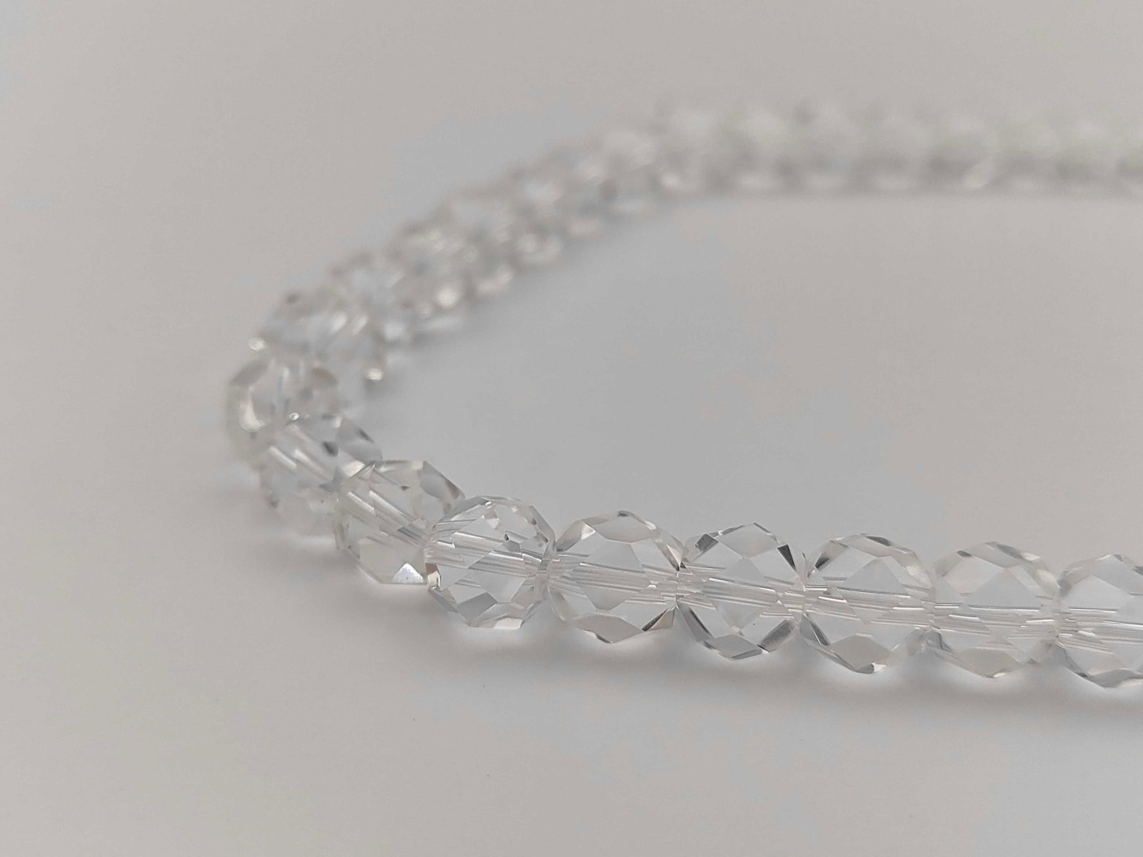 Vintage Graduated Faceted Rock Crystal Necklace with Silver Clasp: Vintage graduated bead necklace featuring faceted clear rock crystal beads. The beads are arranged in a size-graduated strand and secured by an oval filigree fishhook slide clasp. The clasp features e