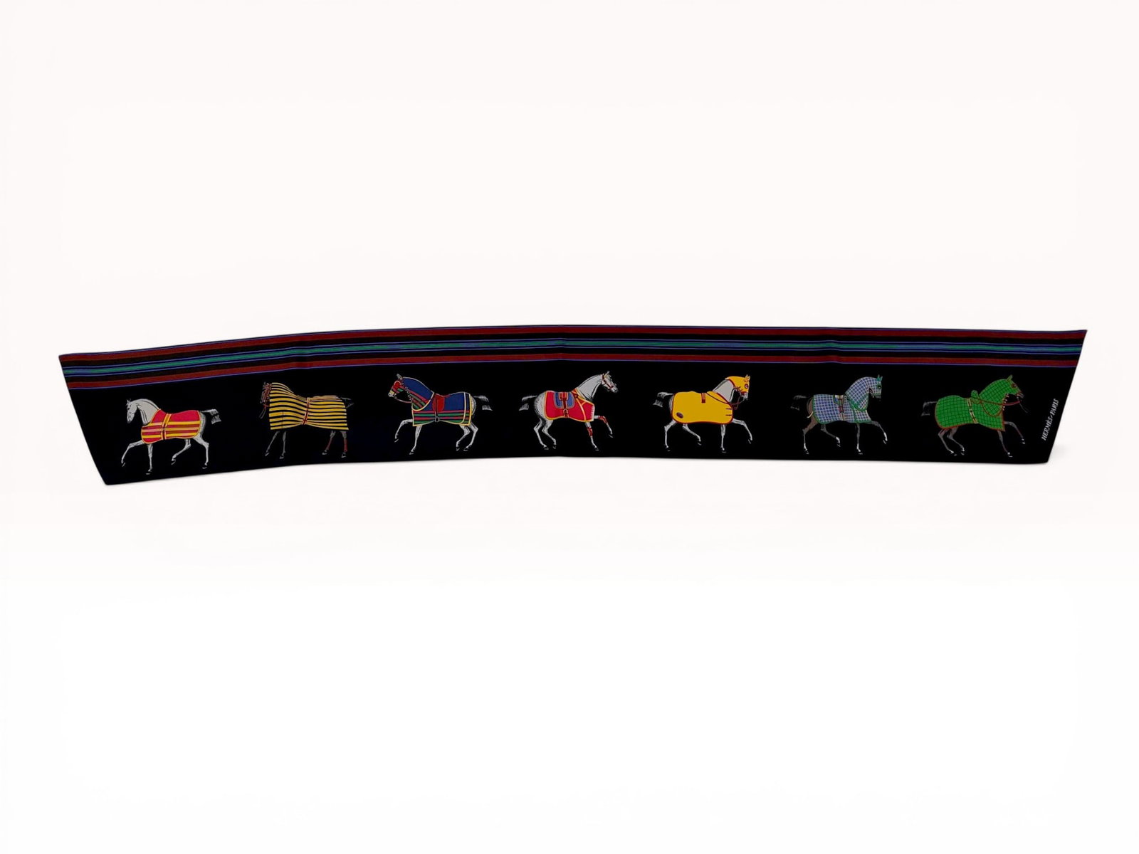 Hermes Couvertures et Tenues de Jour Silk Twilly Scarf: Hermes silk Twilly scarf featuring the Couvertures et Tenues de Jour pattern designed by Jacques Eudel. The double-sided design displays seven horses in various blankets on a black ground with a yello