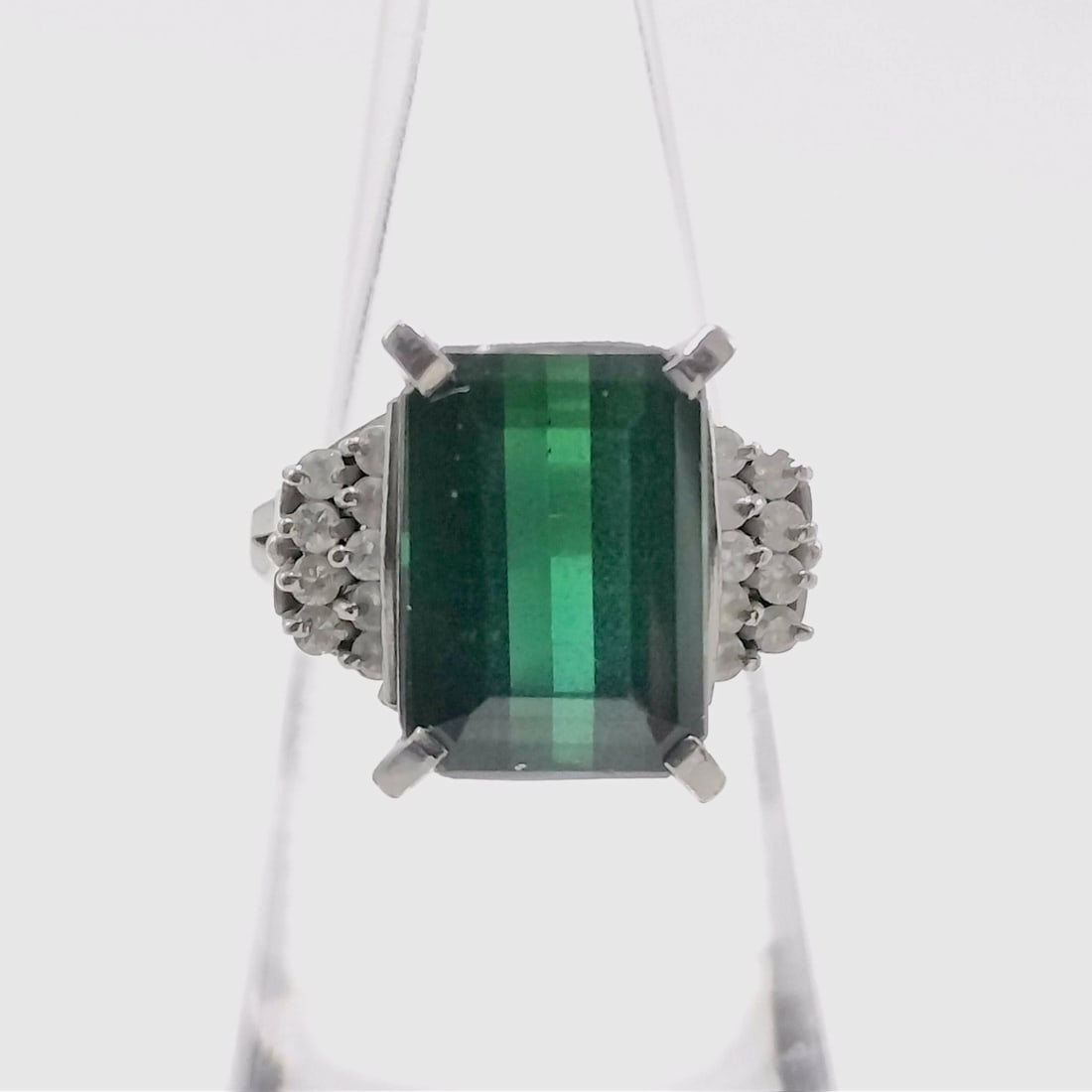 Vintage Platinum 7.66ct Green Tourmaline and Diamond Cocktail Ring: Vintage mid-to-late 20th century cocktail ring featuring a rectangular emerald-cut green tourmaline centered between clusters of round-cut diamonds. The platinum mount is designed with split shoulders