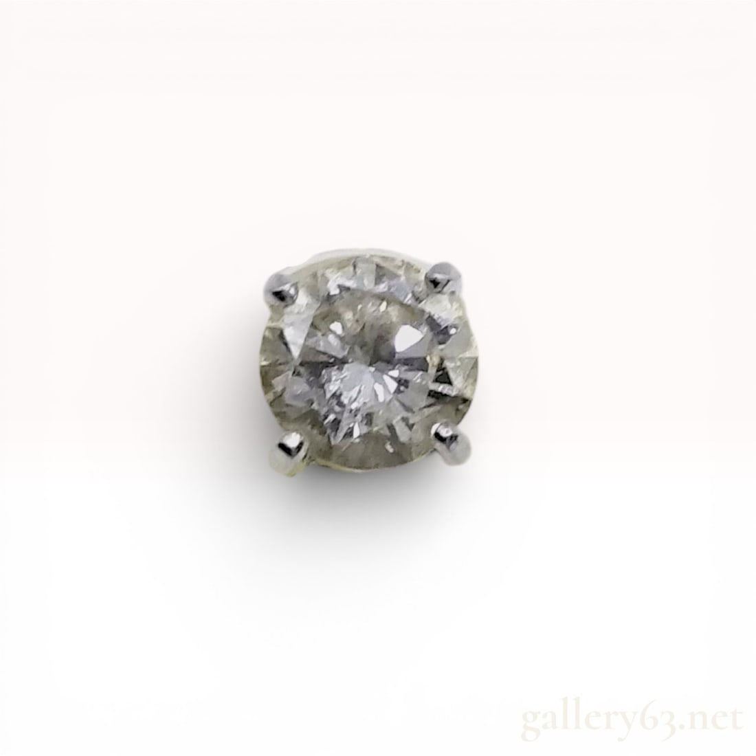 Single Platinum and Round Brilliant-Cut Diamond Stud Earring: Single solitaire stud earring featuring a round brilliant-cut diamond. The gemstone is secured in a four-prong platinum basket setting and displays a noticeable yellowish tint and internal inclusions.