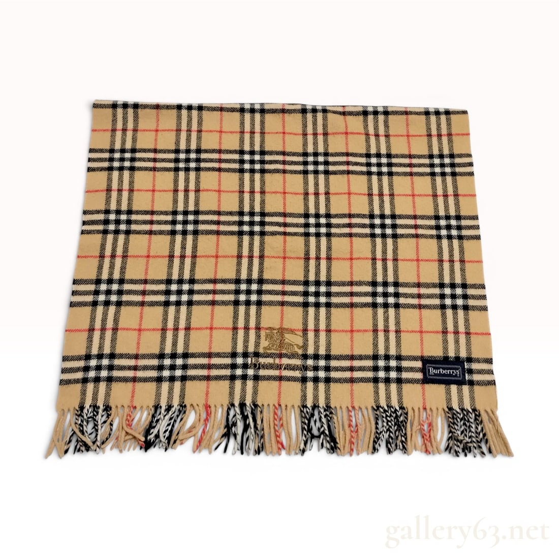 Vintage Burberrys Nova Check 100% Wool Scarf: This vintage Burberrys scarf is crafted from 100% pure new wool and features the classic Nova Check pattern, consisting of a tan ground with intersecting black, white, and red stripes. The body of the