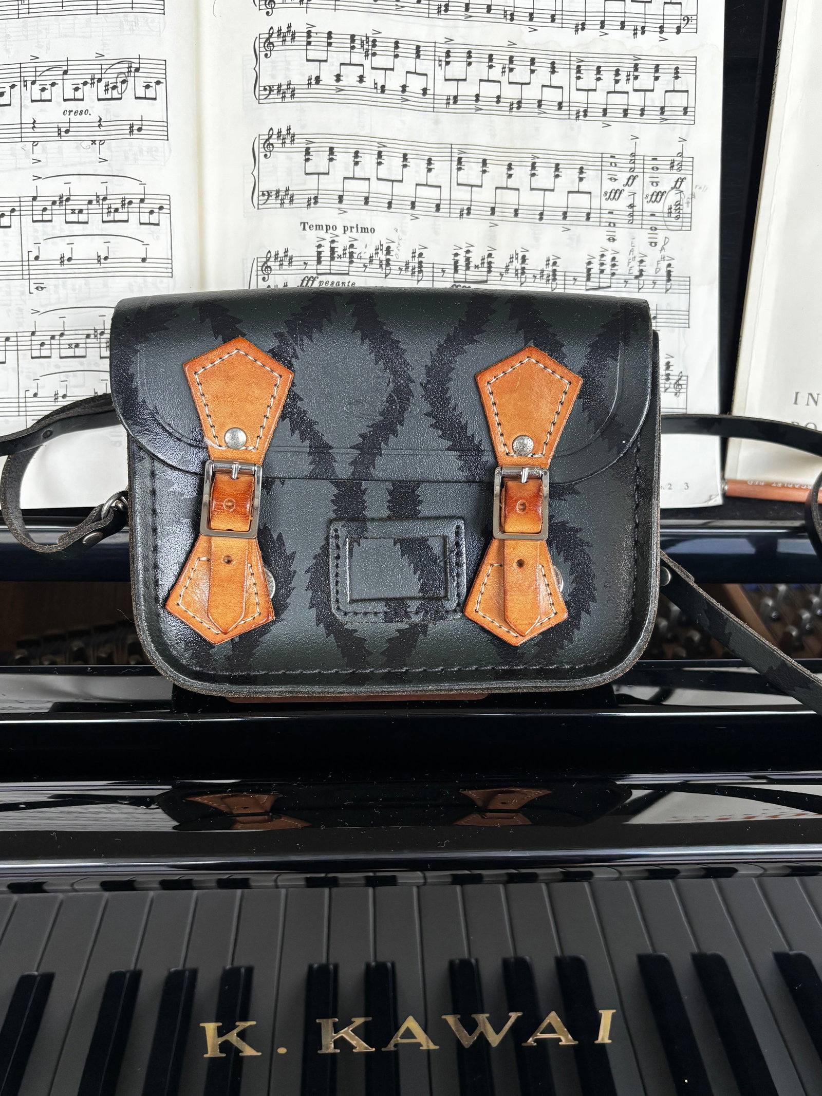 The Cambridge Satchel Company x Vivienne Westwood Tiny Satchel in Squiggle Print: A collaborative small-format satchel bag from The Cambridge Satchel Company and Vivienne Westwood. The bag is crafted from black leather featuring a black screen-printed squiggle pattern throughout th