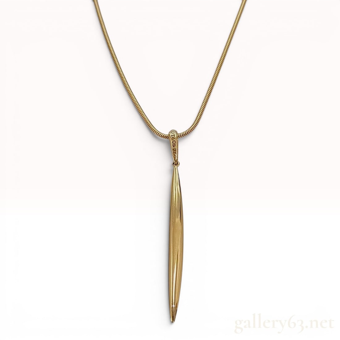 Tiffany & Co. 18K Yellow Gold Feather Pendant Snake Chain Necklace: A Tiffany & Co. 18 karat yellow gold pendant necklace featuring a highly polished feather-style pendant. The elongated and tapered pendant is suspended from a flexible round snake chain. The piece is 