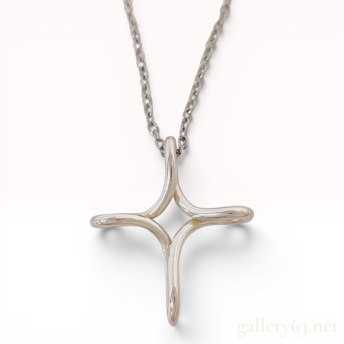 Tiffany and Co. Elsa Peretti Sterling Silver Infinity Cross Pendant Necklace: This sterling silver necklace features a pendant designed by Elsa Peretti for Tiffany and Co. in the Infinity Cross pattern. The pendant is a three-dimensional, openwork four-pointed cross design with