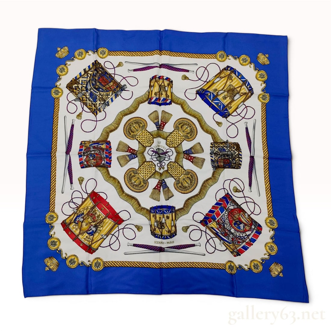Hermes Les Tambours Silk Carre 90 Scarf: Hermes silk Carre 90 scarf featuring the Les Tambours design by artist Joachim Metz. The ivory field displays an array of military drums and epaulettes, framed by a vibrant blue border with gold-toned