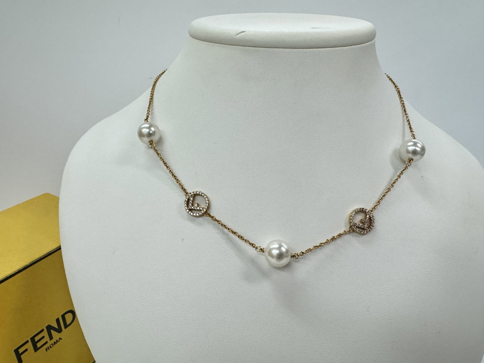 Fendi F Is Fendi Pearl and Crystal Station Necklace: Fendi gold-tone station necklace from the F Is Fendi collection. The fine cable chain is punctuated by four round white simulated pearls and two circular charms featuring the signature F logo bordered