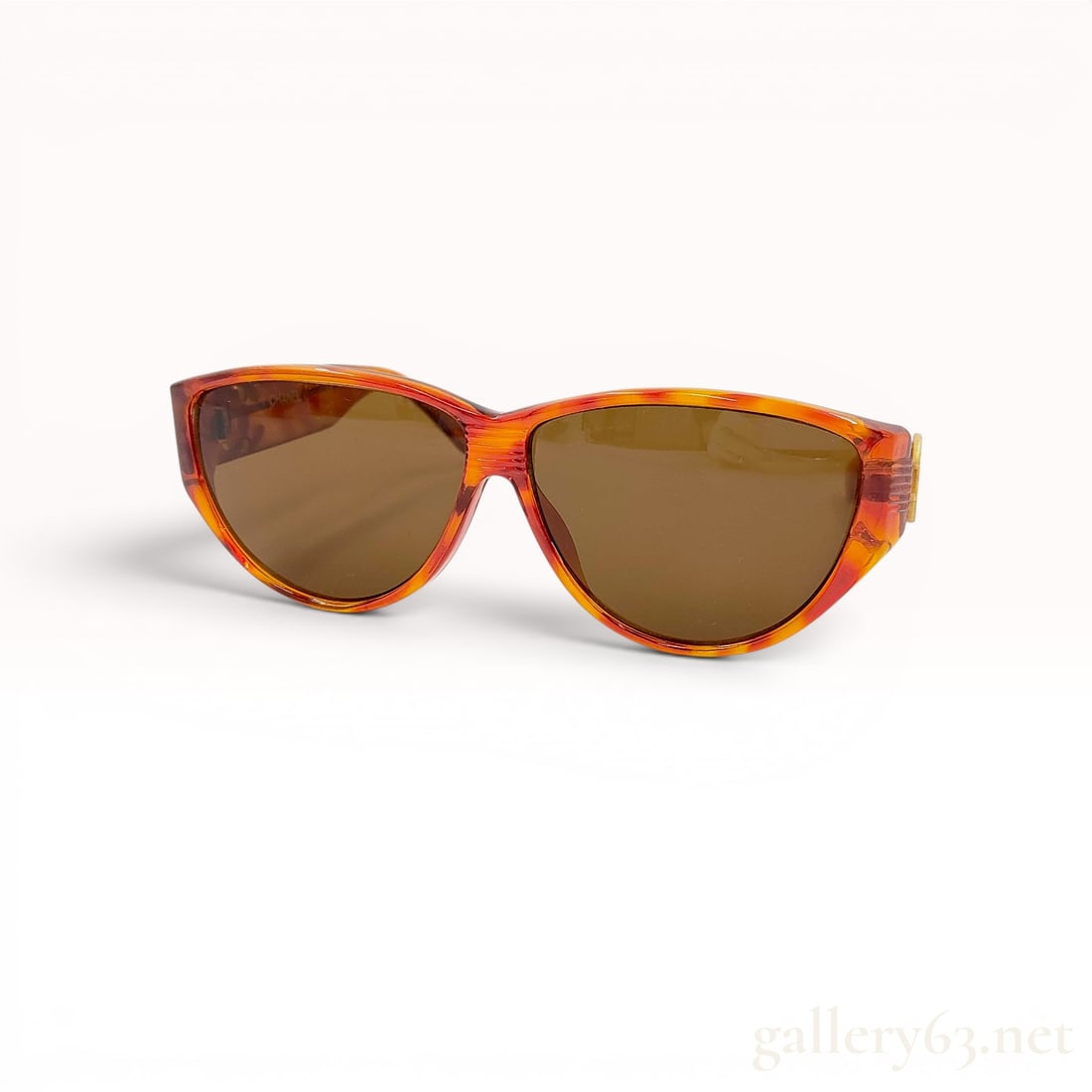 Vintage Chanel Model 0016 Tortoiseshell Acetate Sunglasses, Circa 1990s: Chanel vintage sunglasses, model 0016, produced in Italy during the 1990s. The wrap-around frames feature a translucent orange and amber tortoiseshell-patterned acetate construction with brown-tinted 