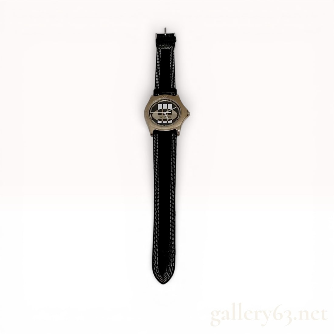 Adidas Reference 10-5762 Quartz Wristwatch: A men's quartz wristwatch by Adidas. The timepiece features a base metal bezel with a stainless steel case back. The dial displays a graphic black, silver, and white checkered pattern with the lowerca