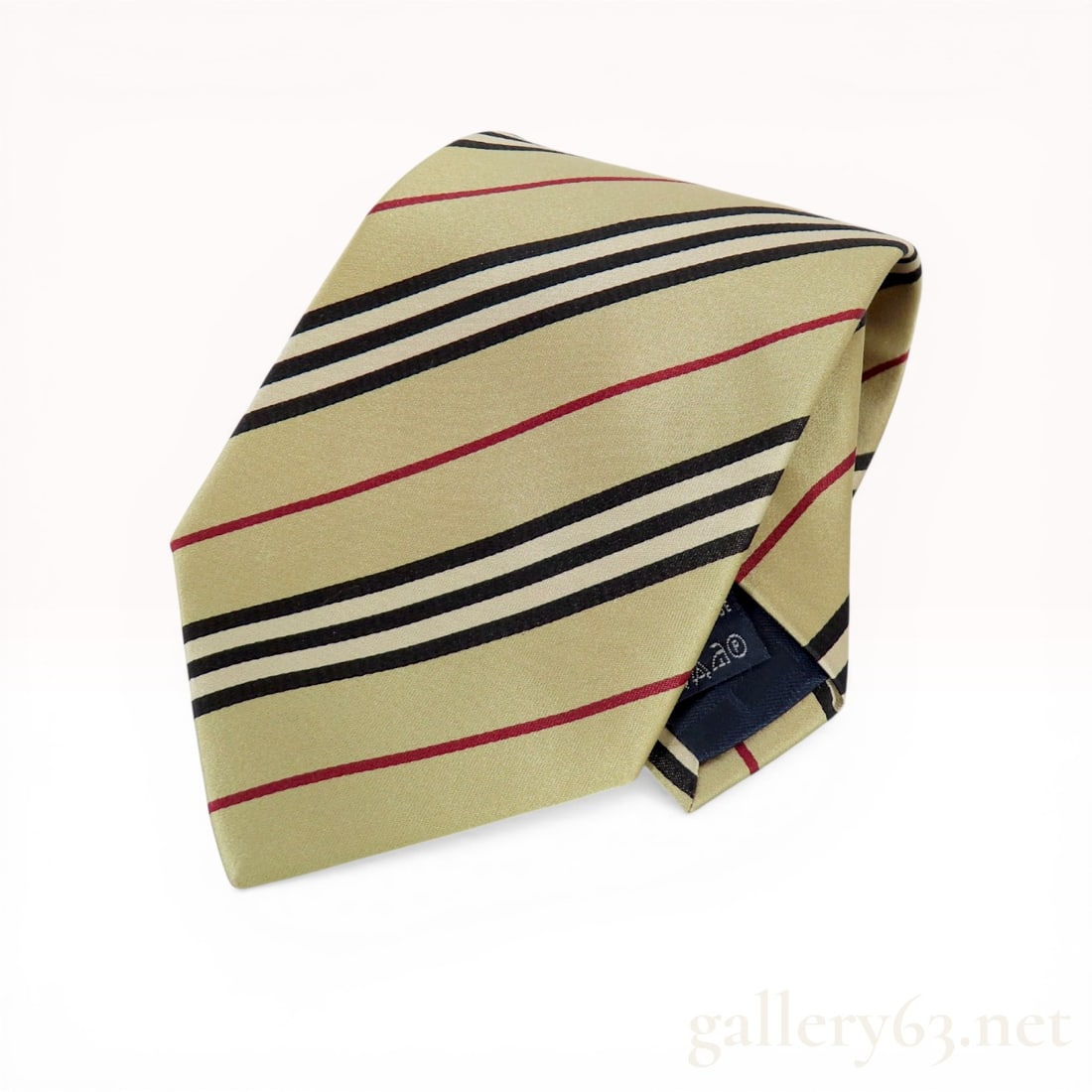 Burberry London Men's Beige Manson Diagonal Stripe Silk Tie: Burberry London men's necktie in the Manson diagonal stripe pattern. The 100% silk construction features grouped black and white stripes alternating with single red stripes on a tan ground. The interi