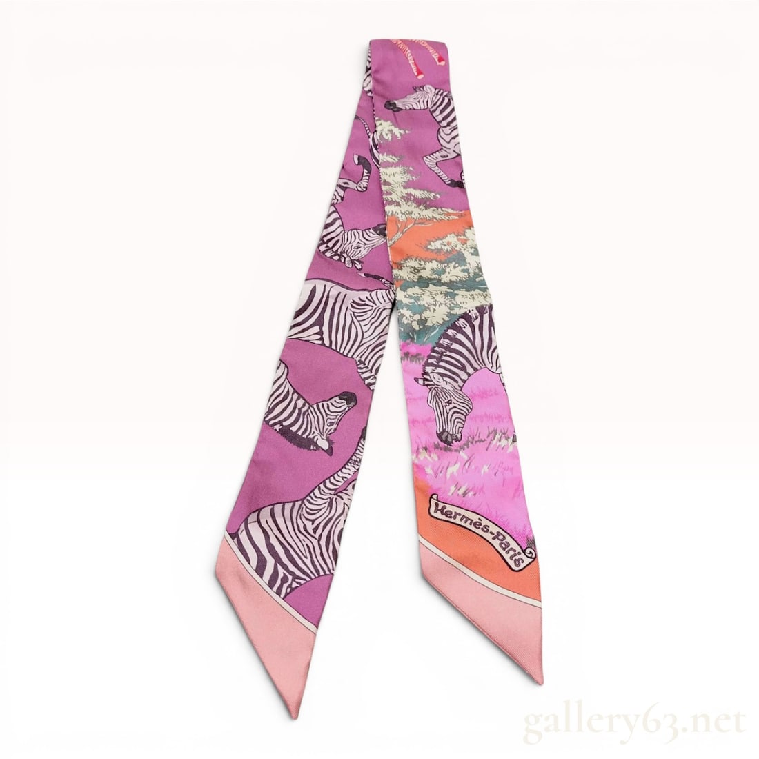 Hermes Silk Twilly Scarf Les Zebres Pattern by Alice Shirley: A designer silk twilly scarf by Hermes featuring the Les Zebres pattern designed by Alice Shirley. The narrow, ribbon-style scarf displays various zebras in dynamic poses amidst a stylized landscape o